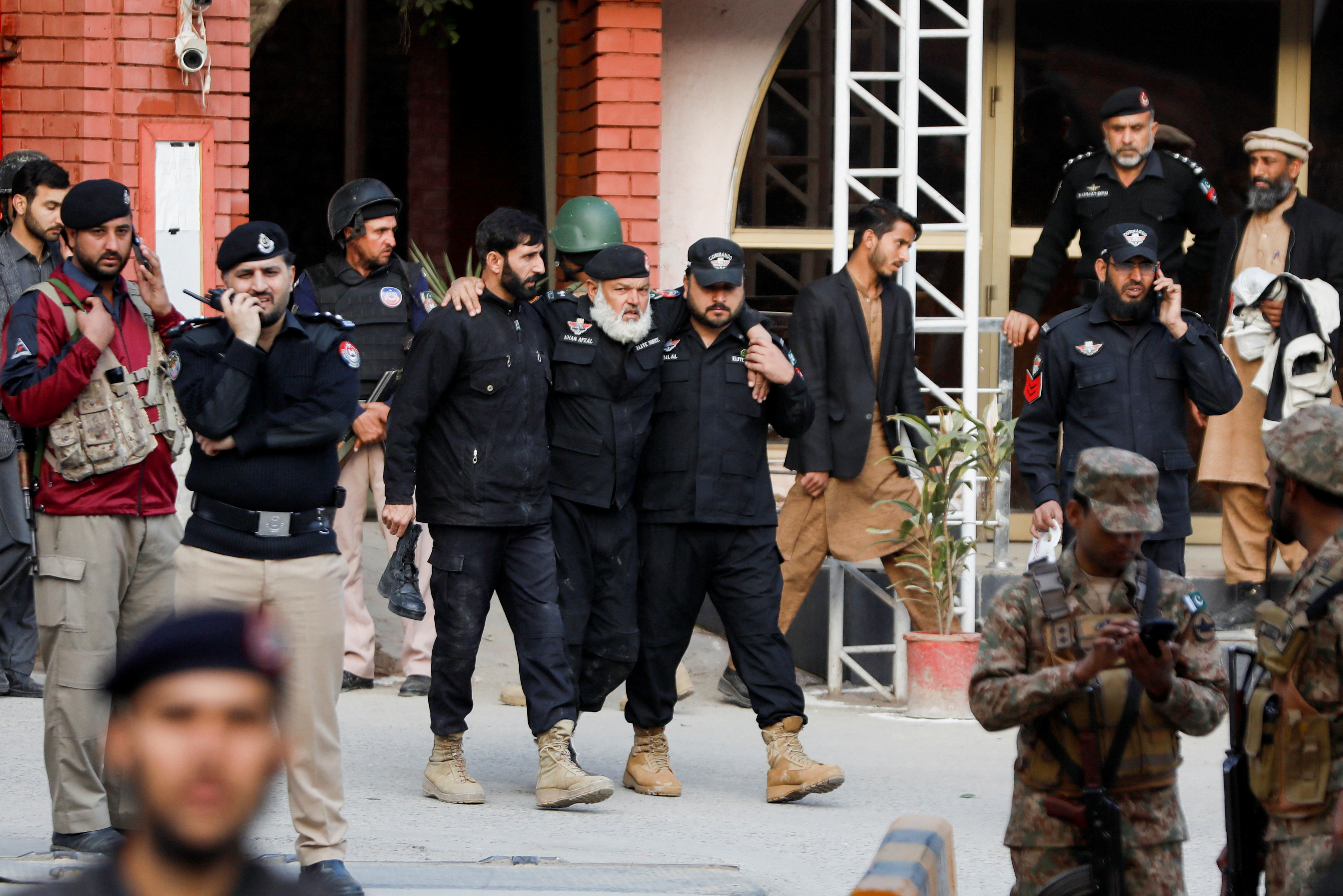 Police officers assist an injured officer, after a suicide blast in a mosque in Peshawar