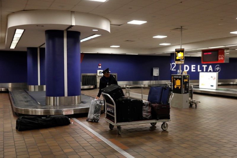 A baggage claim employee grabs bags from an empty baggage claim area in Delta terminal at LaGuardia Airport in New York