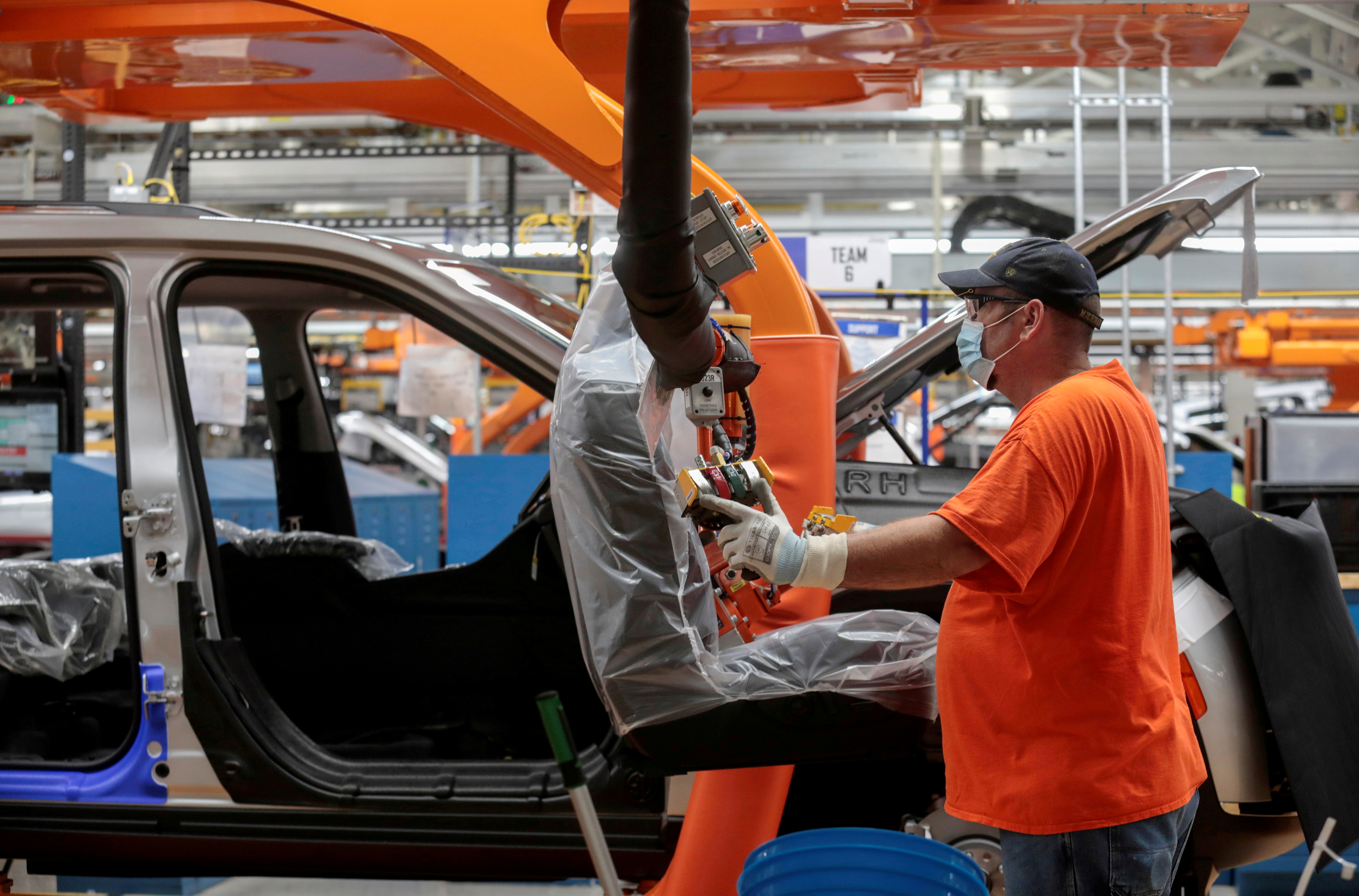 A worker prepares to install seats in a 2021 Jeep Grand Cherokee L frame in Detroit, Michigan