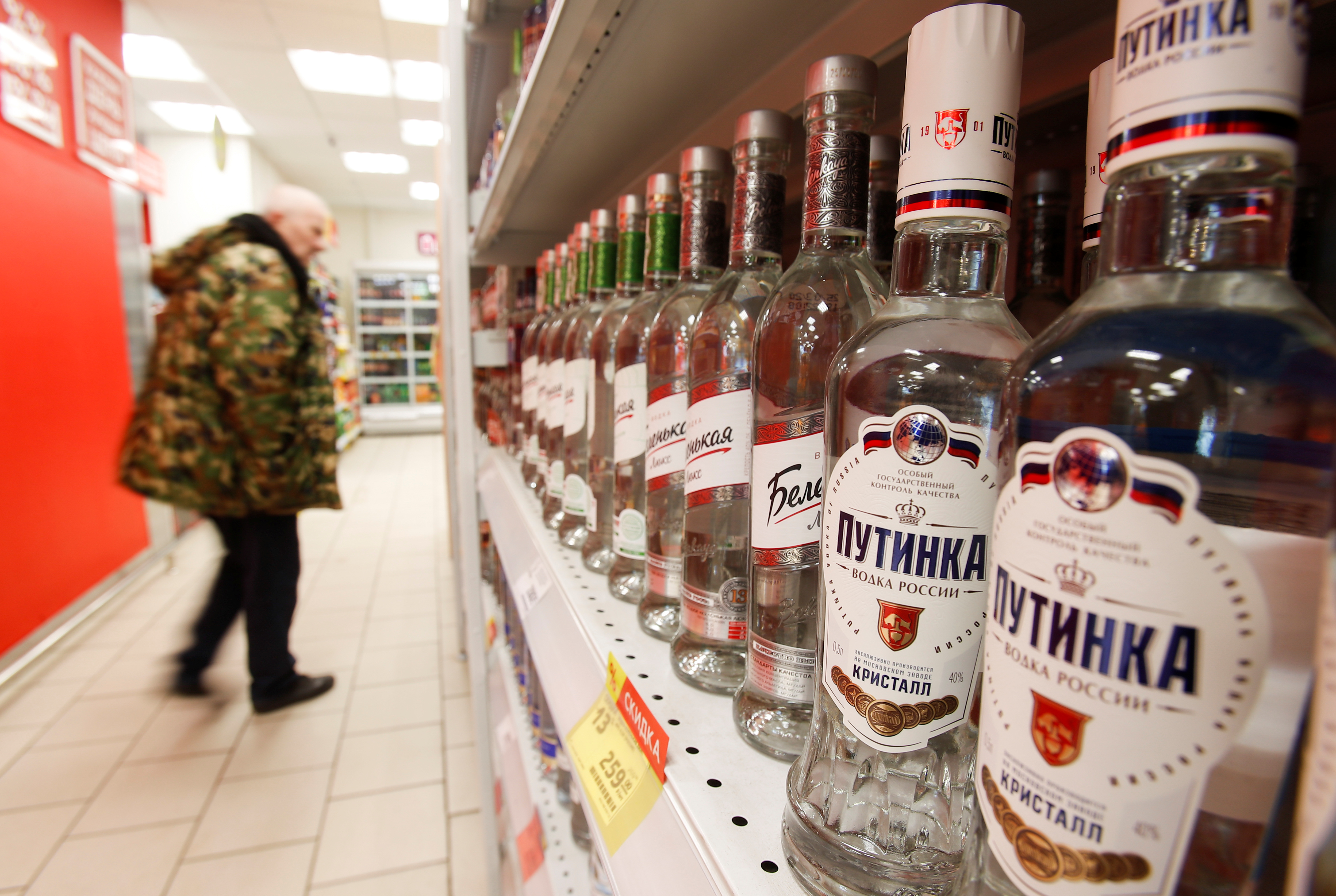 A customer walks past shelves with bottles of vodka in a supermarket in Moscow