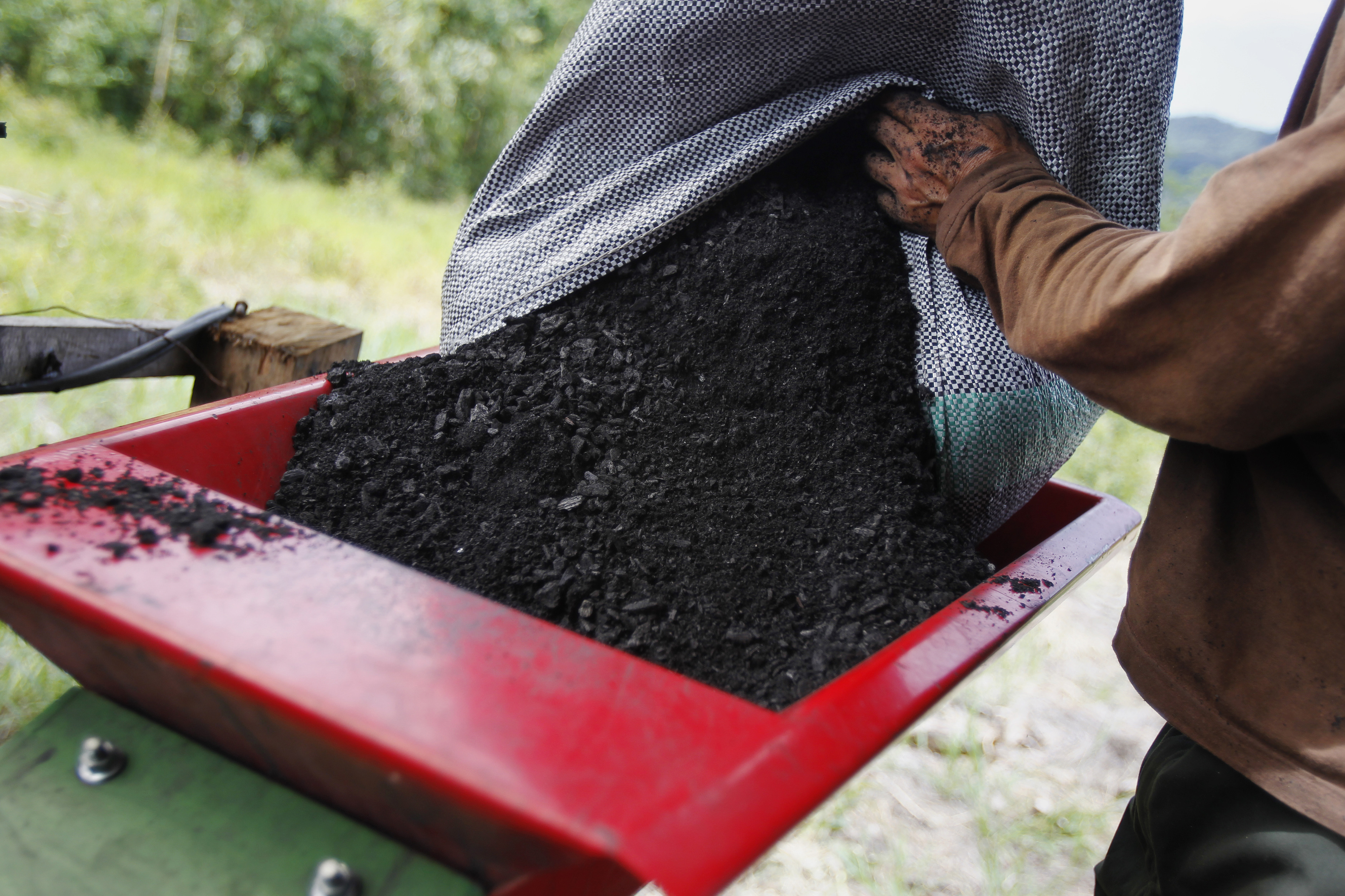 A worker prepares to grind biochar extracted from an oven at the Villa Carmen Biological Station in Pilcopata