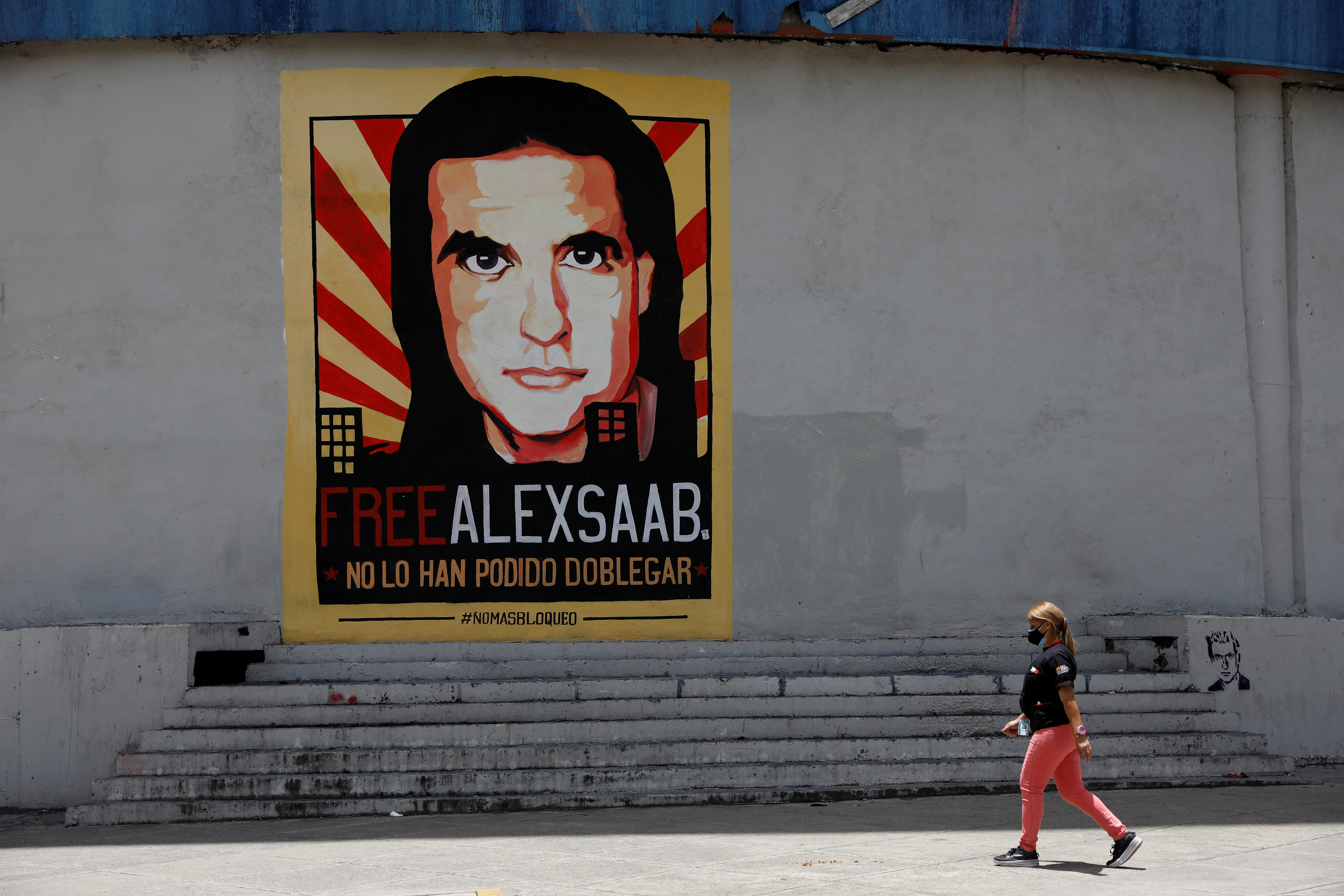 A woman walks by a mural in support of the liberation of Colombian businessman and envoy Alex Saab, who is detained in Cape Verde on charges of laundering money for the government of Venezuelan President Nicolas Maduro, in Caracas