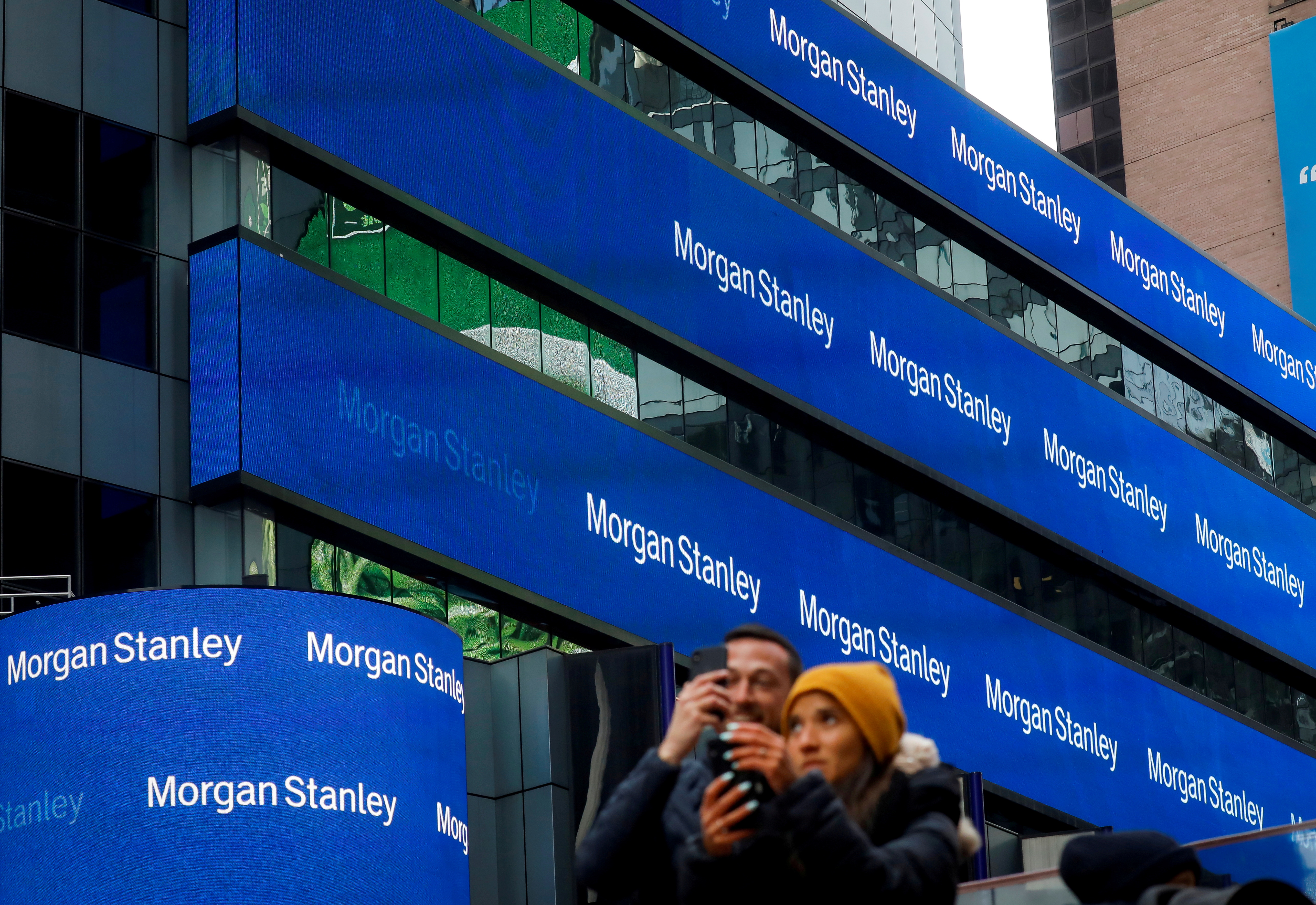 People take photos by the Morgan Stanley building in Times Square in New York