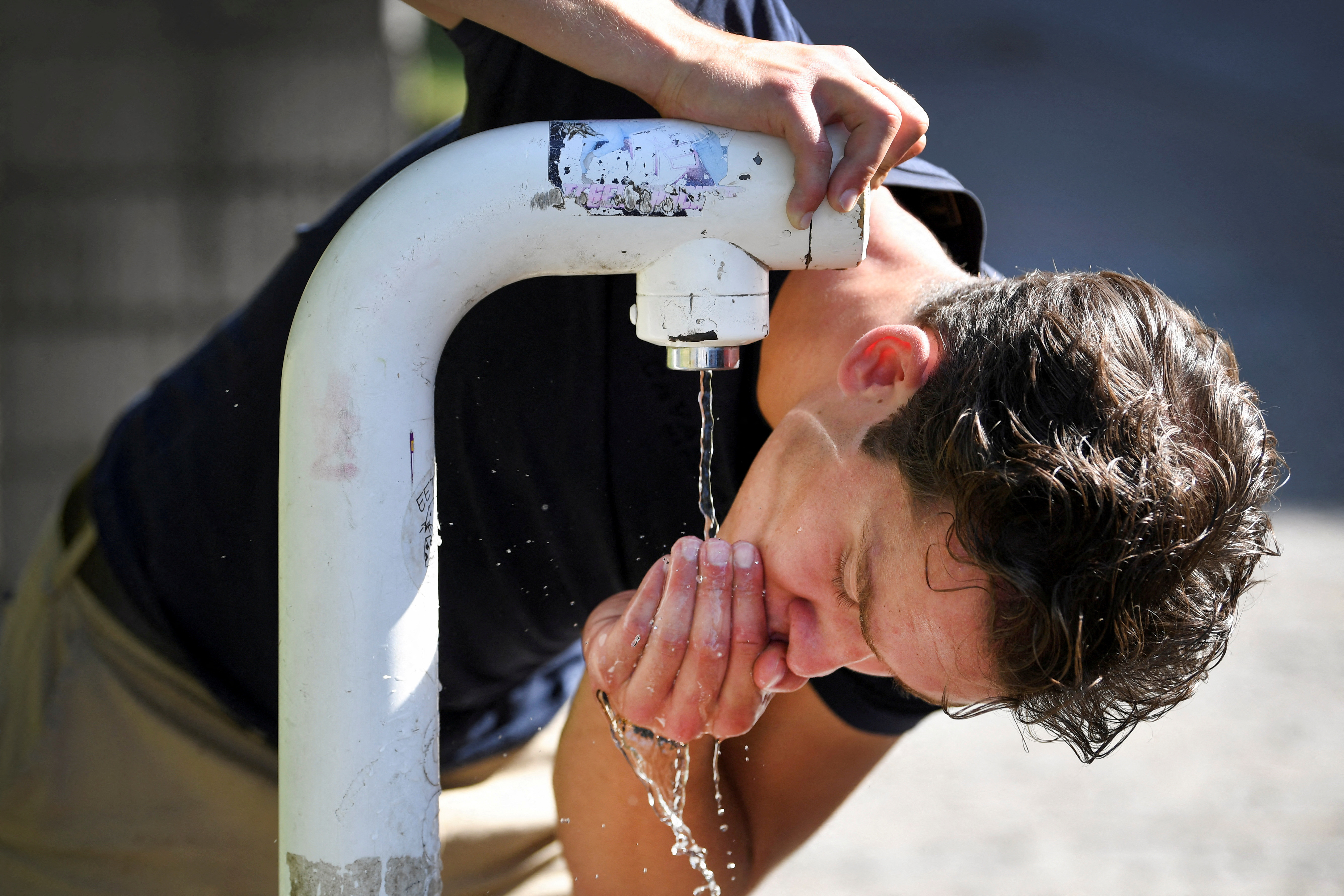 A man drinks water from a public drinking establishment during a heatwave in Nijmegen