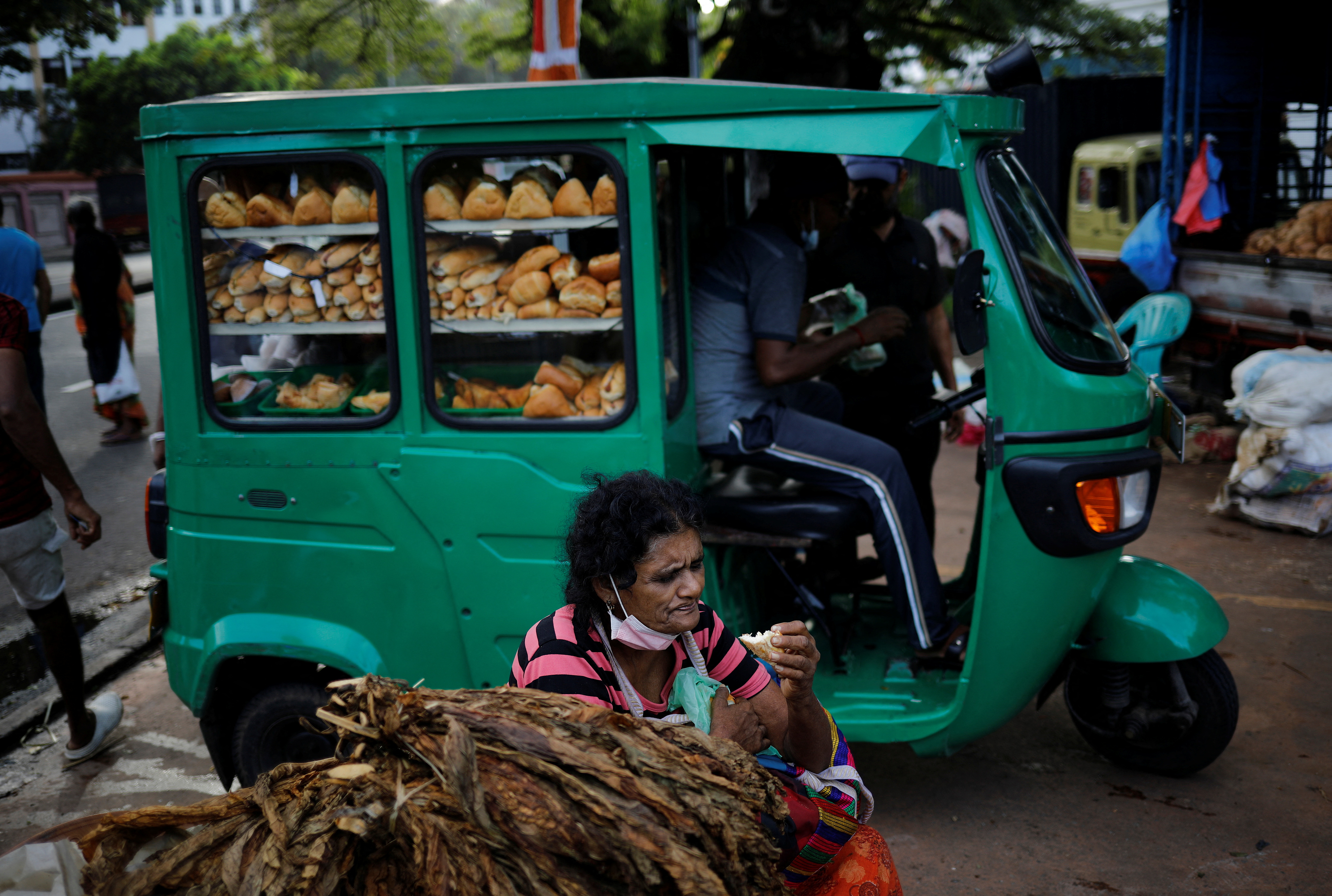 A vendor eats bread as she waits for customers at a vegetable market, amid the country's economic crisis in Colombo
