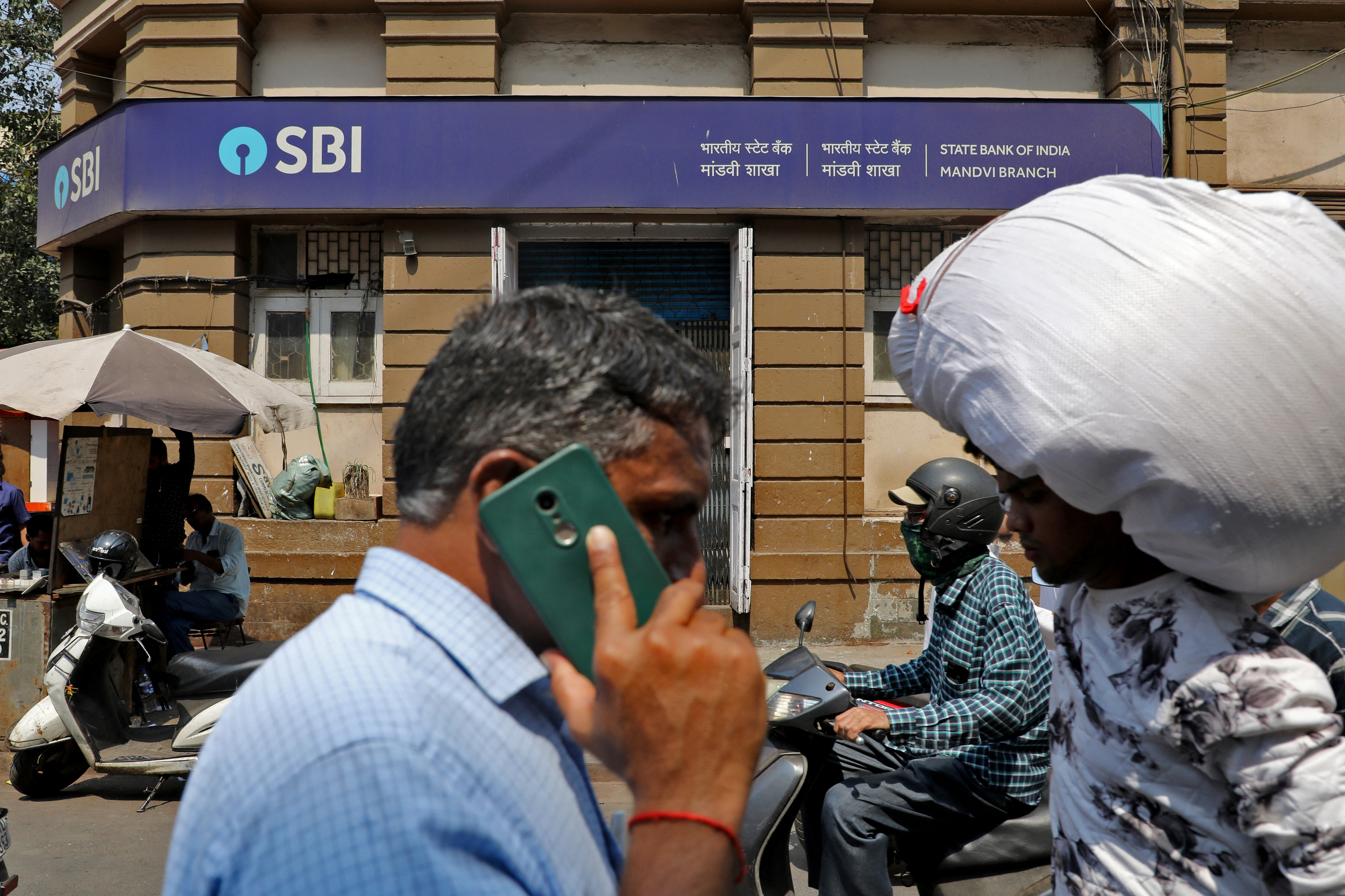 People move past a branch office of SBI in Mumbai