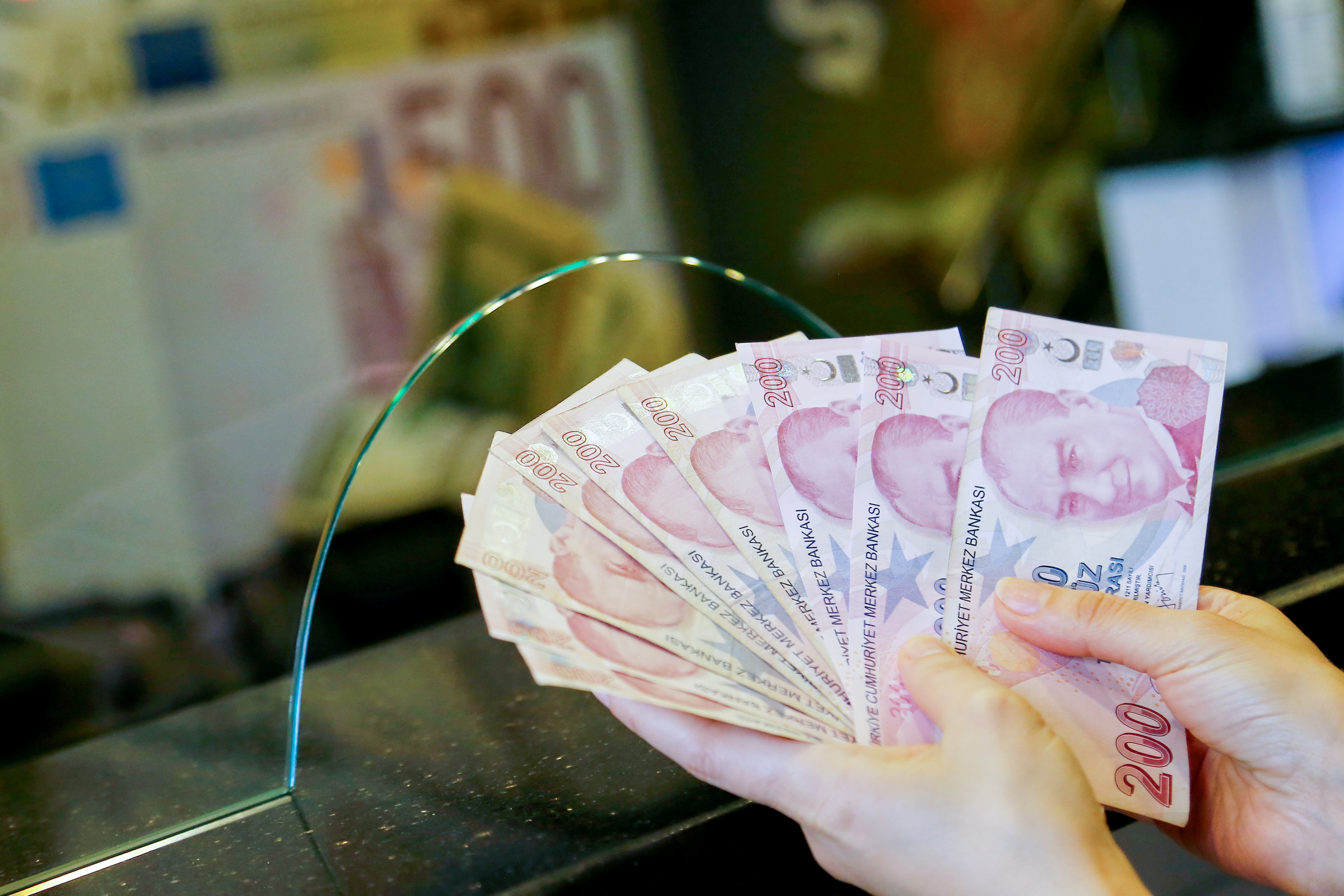 A money changer holds Turkish lira banknotes at a currency exchange office in Ankara