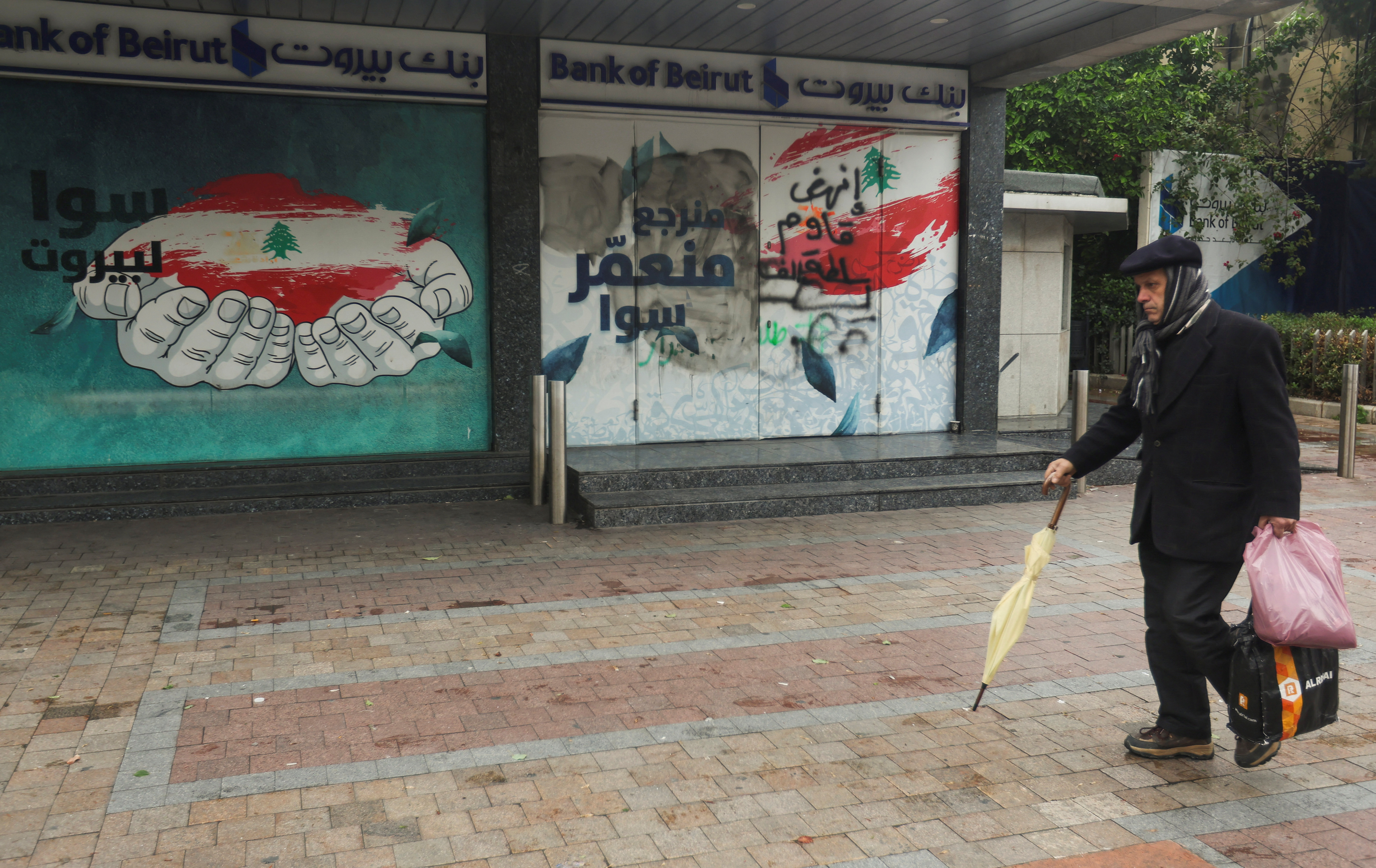 A man walks past a closed Bank of Beirut branch in Sidon