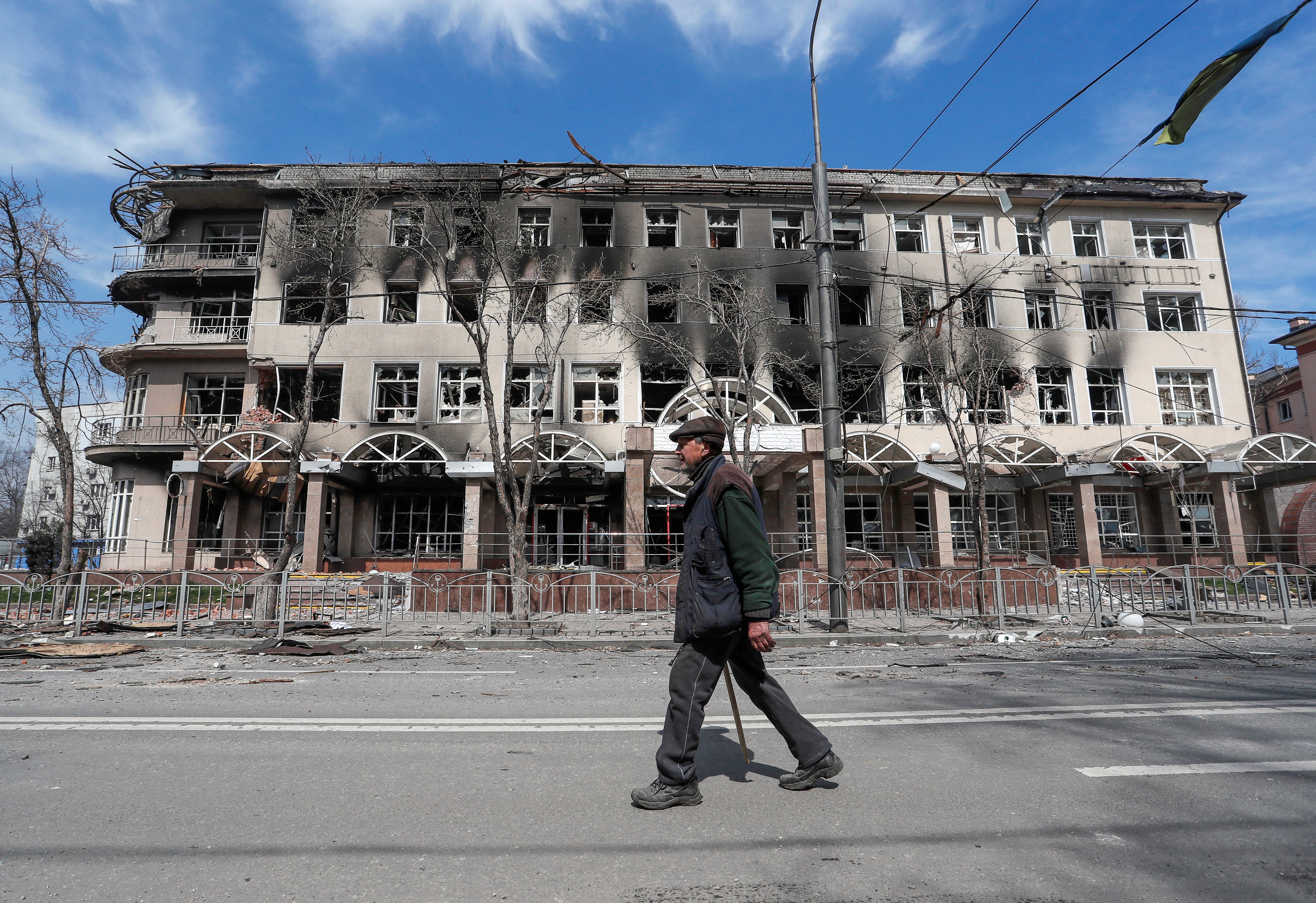 A resident walks near a building destroyed in the course of the Ukraine-Russia conflict, in Mariupol