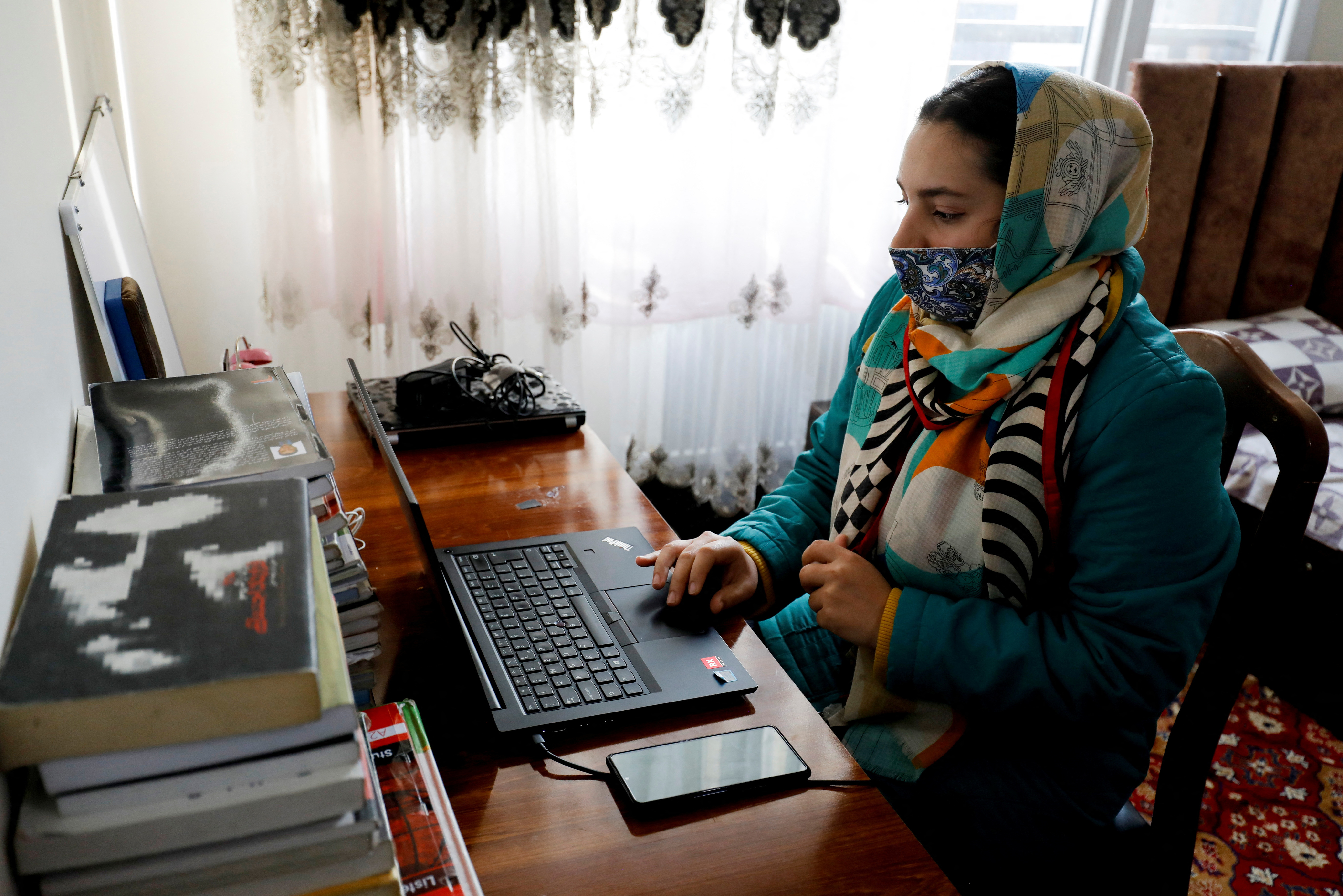 Sana, an Afghan teacher, teaches during an online class, at her house in Kabul