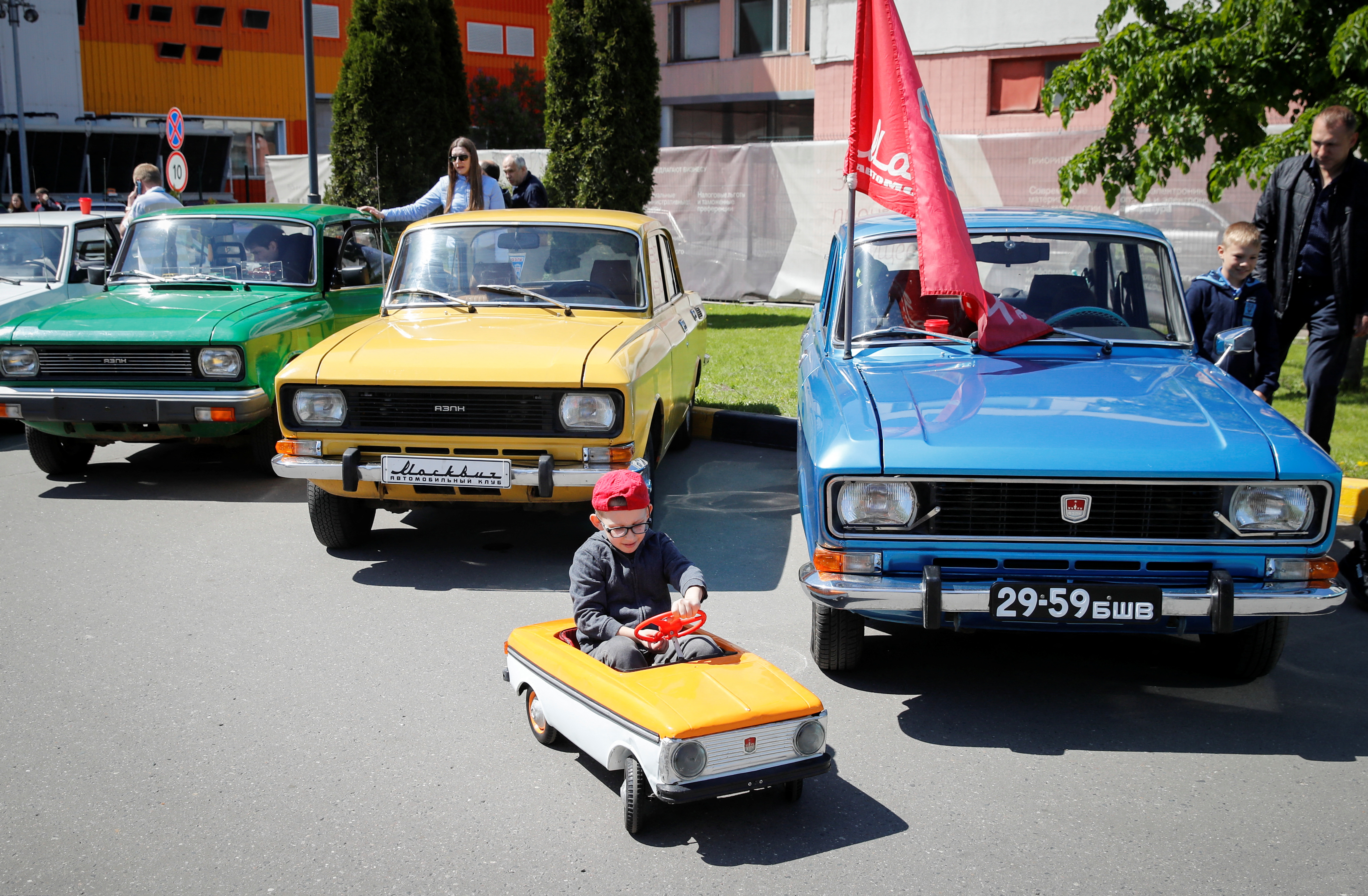 A boy drives a children's car during a gathering of Soviet-era Moskvich cars owners and enthusiasts in Moscow
