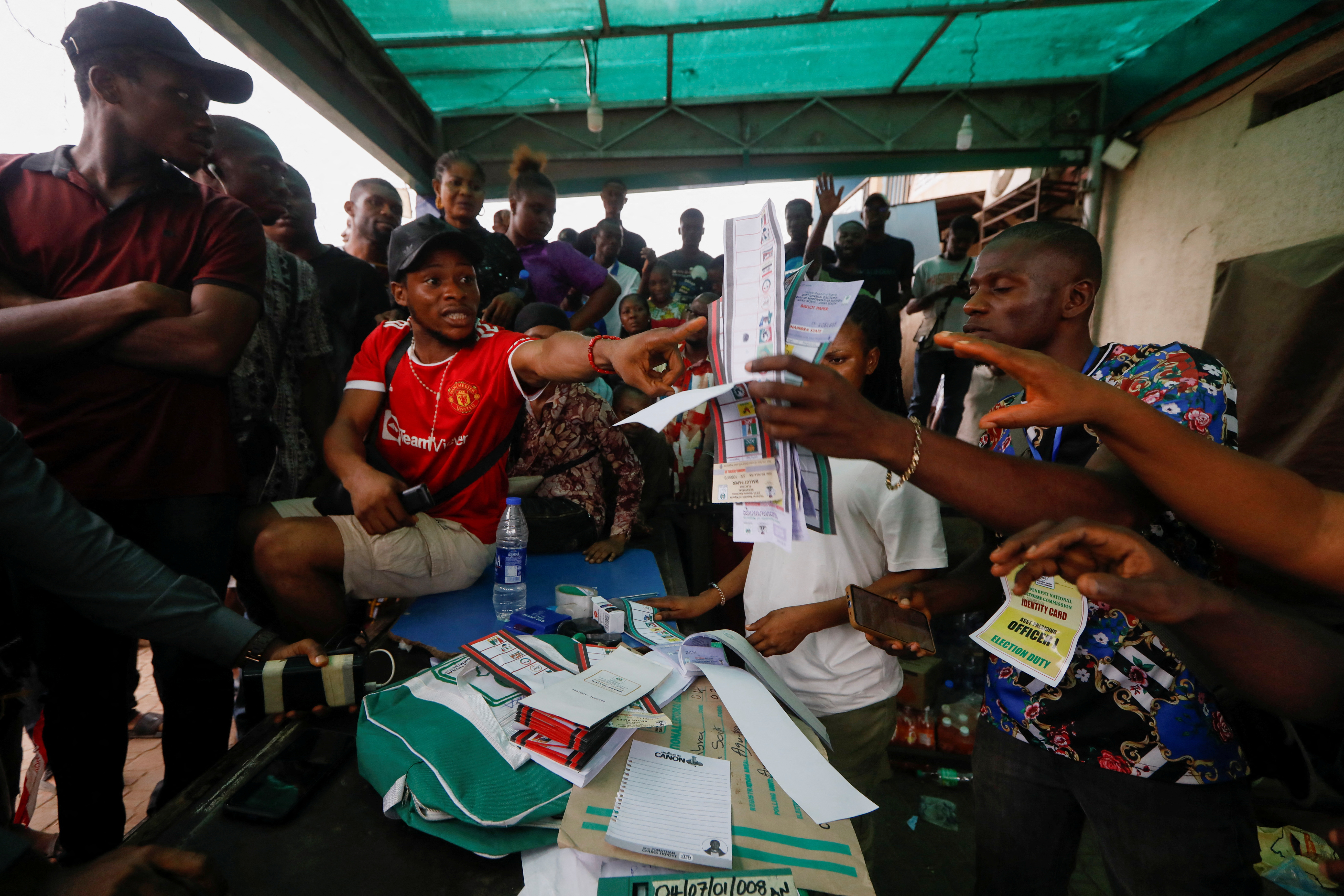 People react during the counting process of Nigeria's presidential election, at a polling unit in Awka