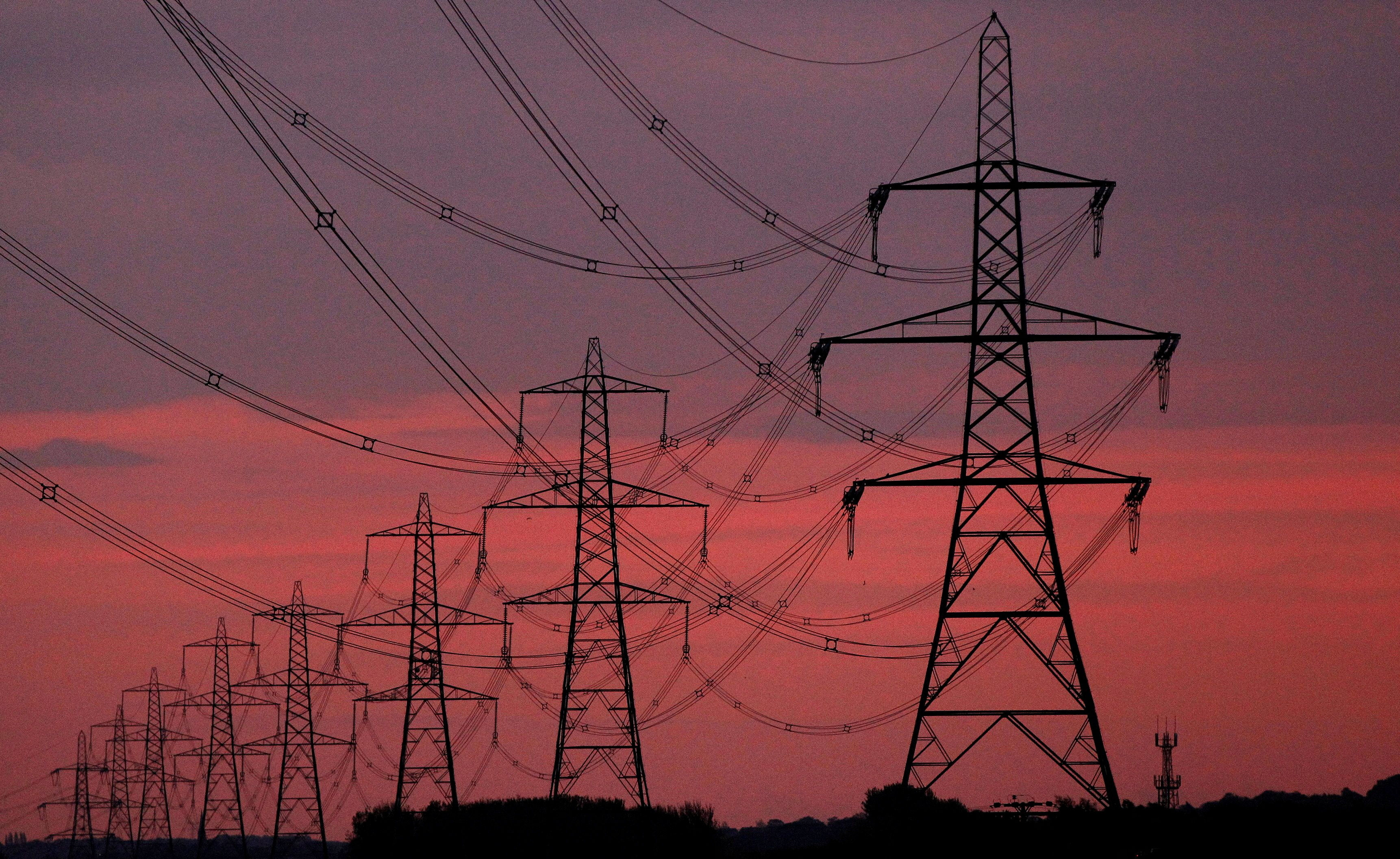 The sun rises behind electricity pylons near Chester