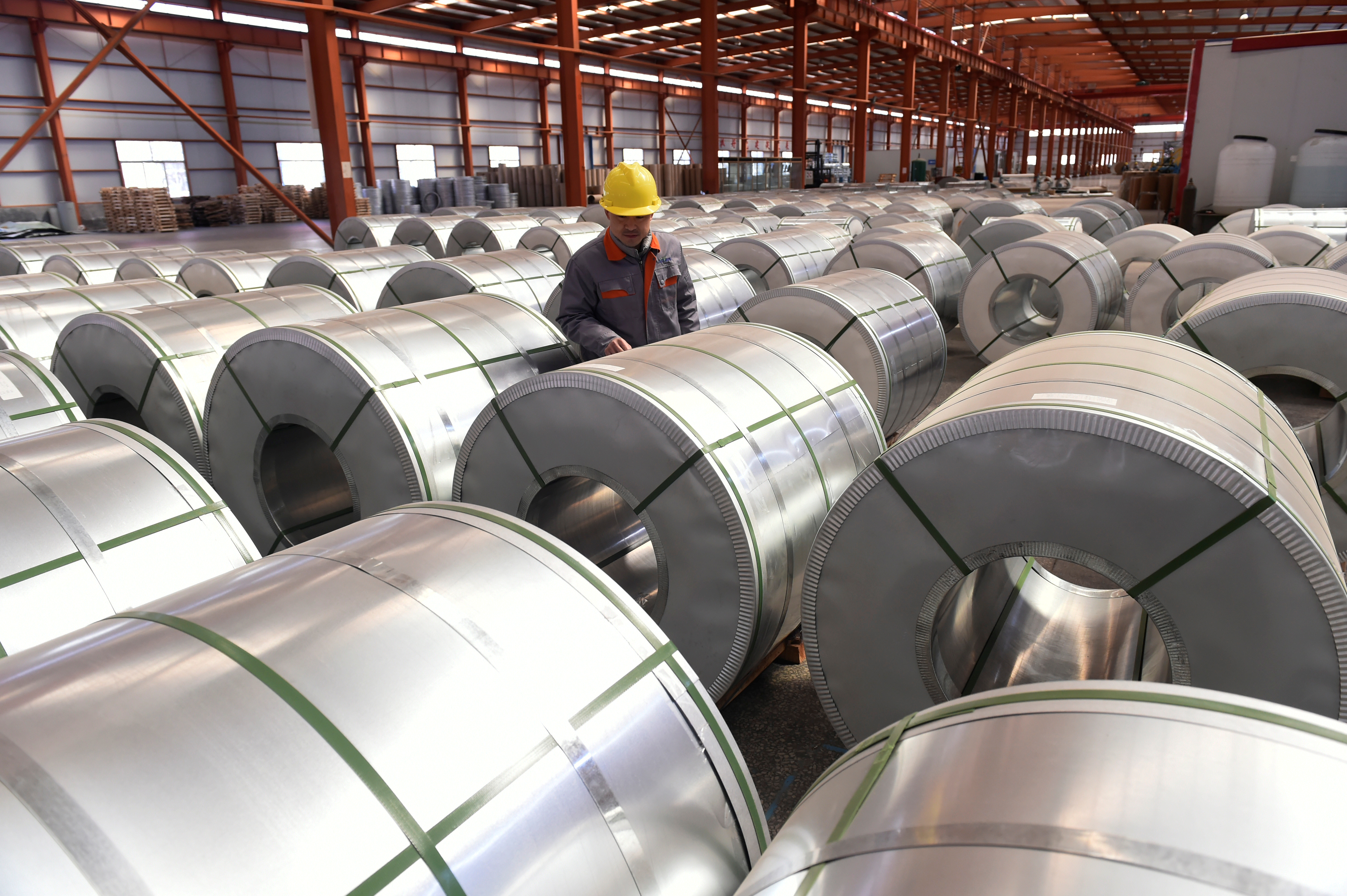 A worker checks aluminium rolls at a warehouse inside an industrial park in Binzhou