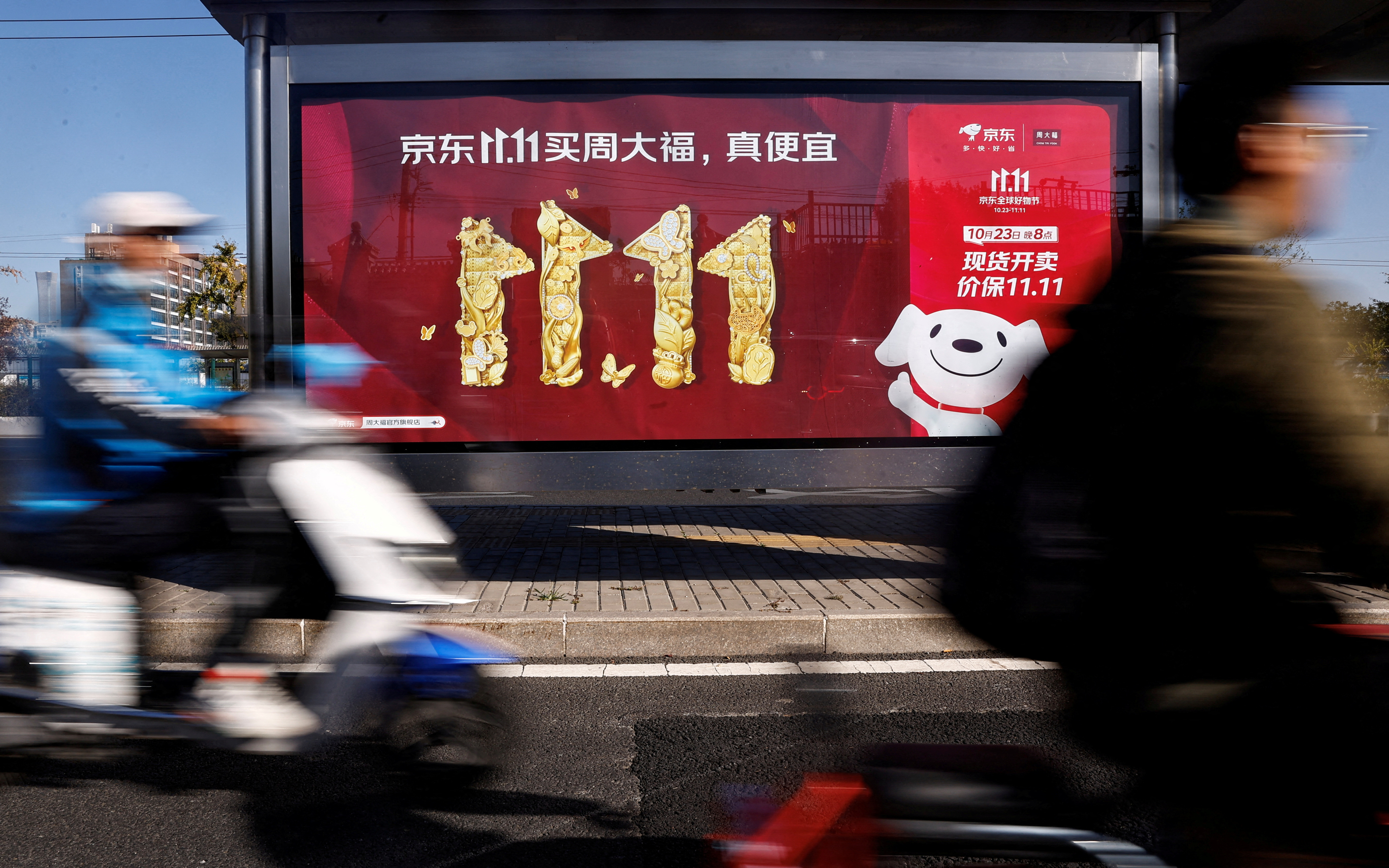 People ride on a scooter past a JD.com's advertisement promoting Singles Day shopping festival, in Beijing