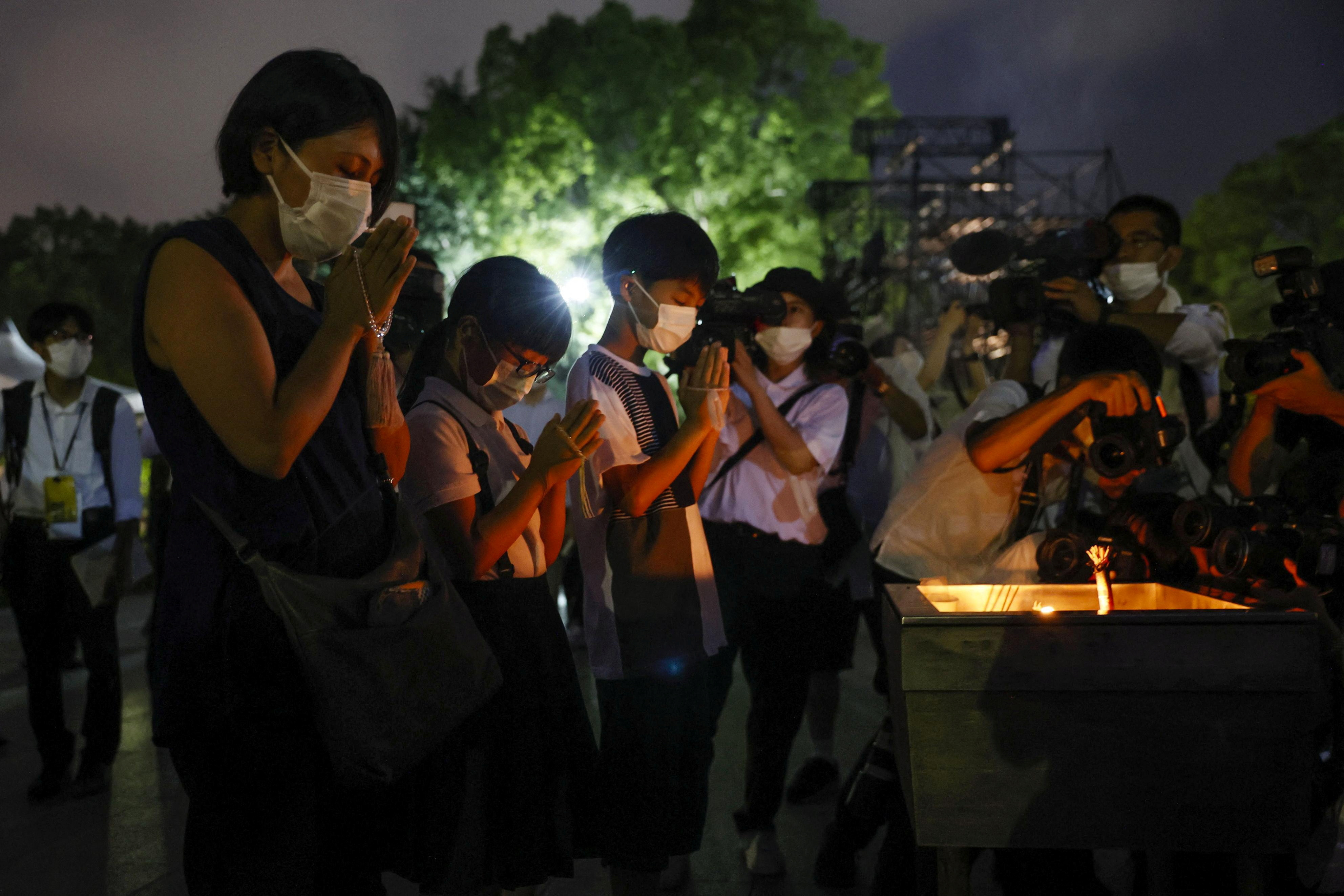 People pray in front of the cenotaph for the victims of the 1945 atomic bombing at Peace Memorial Park in Hiroshima, Japan