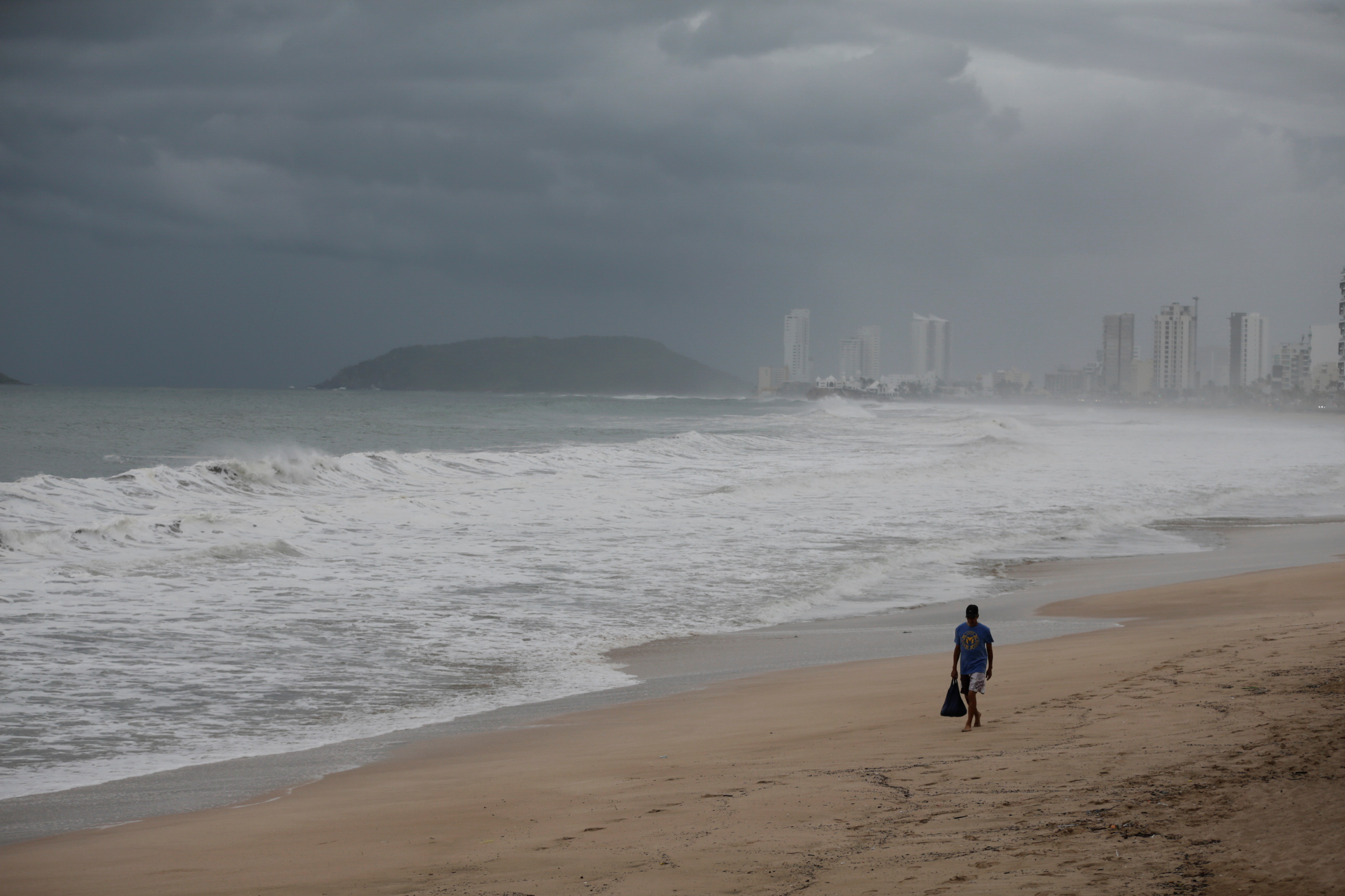 Man walks on a closed beach as storm Pamela approaches the Pacific coast resort, in Mazatlan
