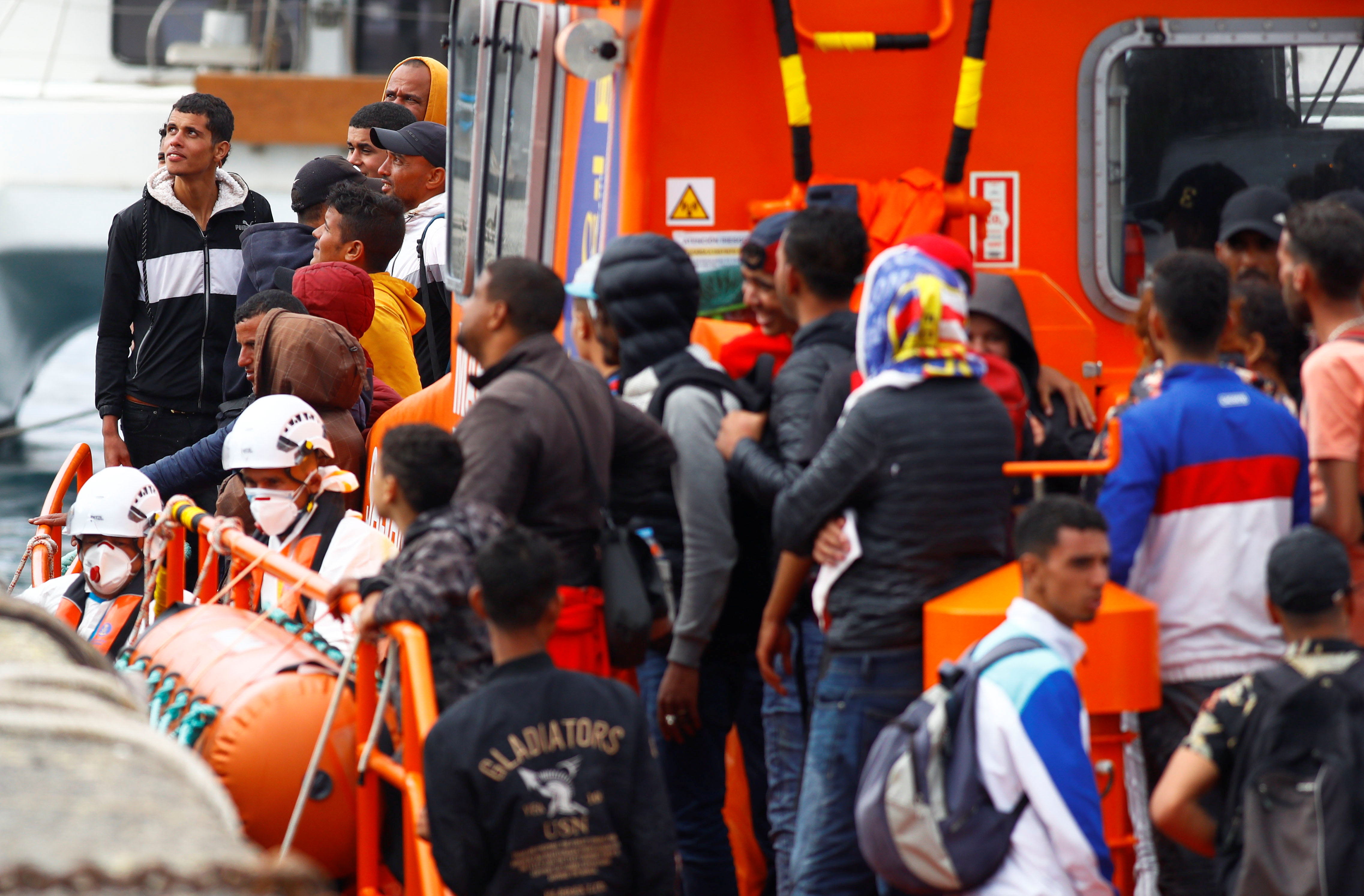 Migrants wait to disembark from a Spanish coast guard vessel in the port of Arguineguin