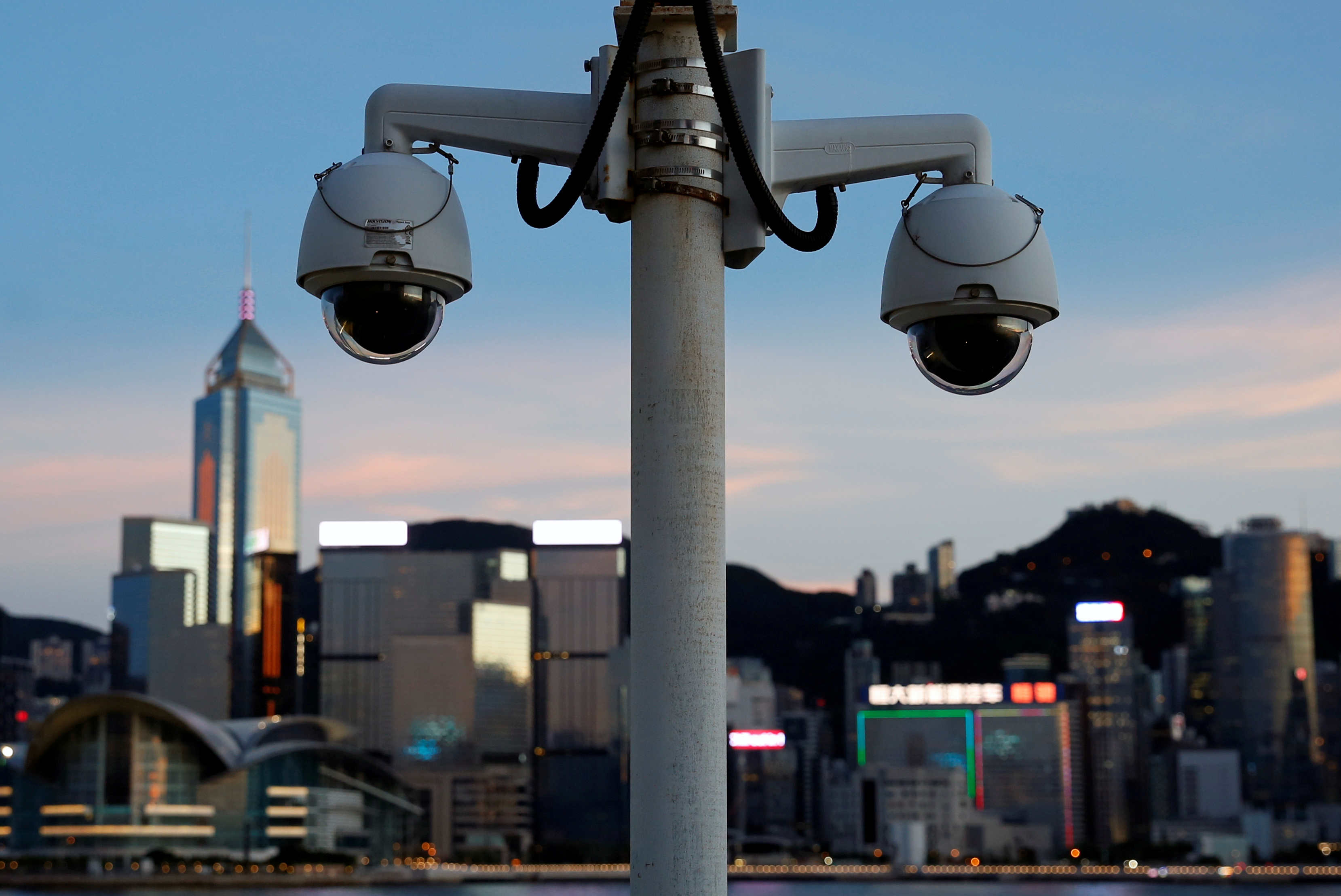 A pair of surveillance cameras are seen along the Tsim Sha Tsui waterfront as skyline buildings stand across Victoria Harbor in Hong Kong, China July 28, 2020. REUTERS/Tyrone Siu/File Photo