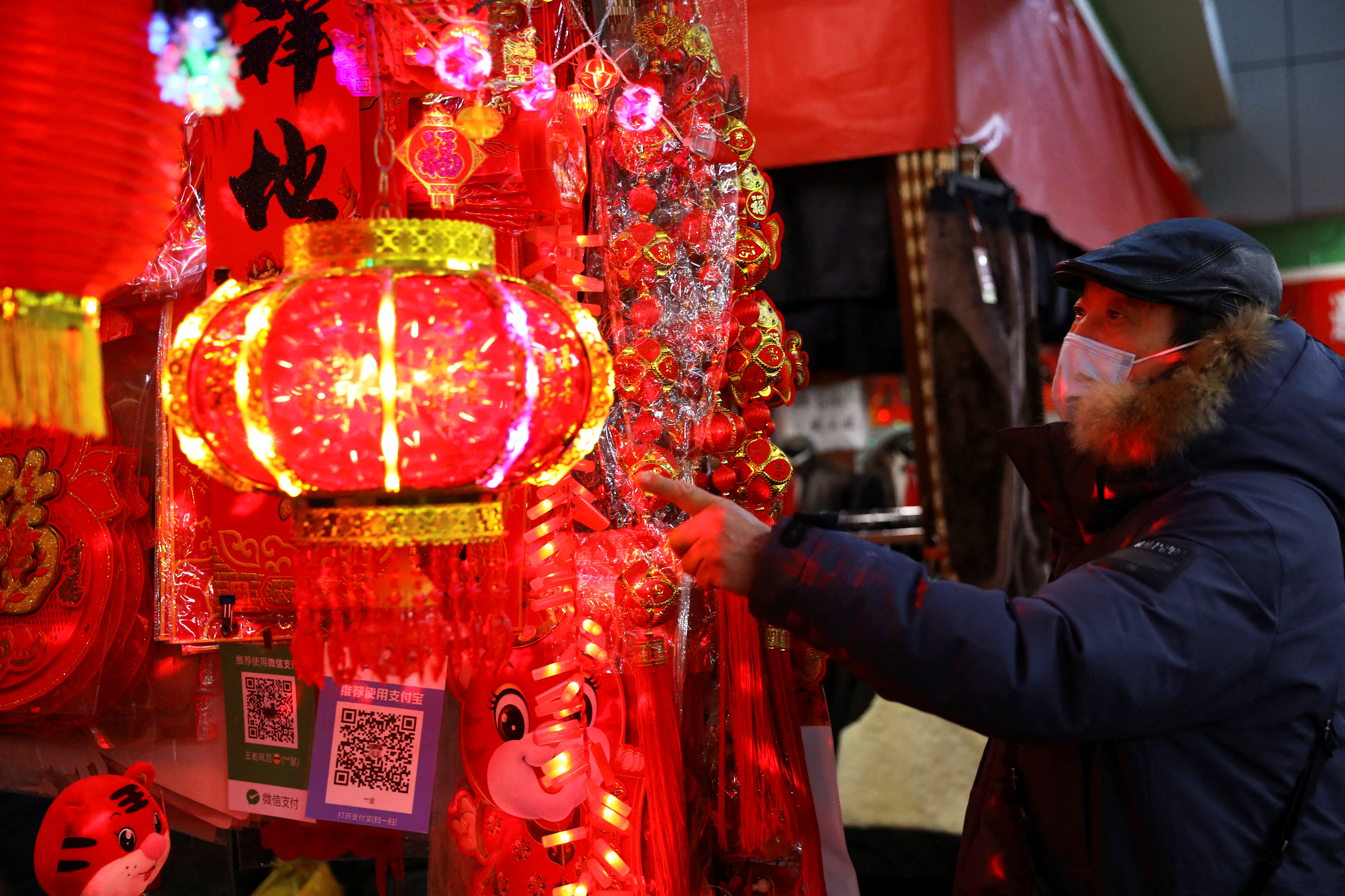 A customer looks at decorations for Chinese Lunar New Year displayed at a stall inside a morning market in Beijing