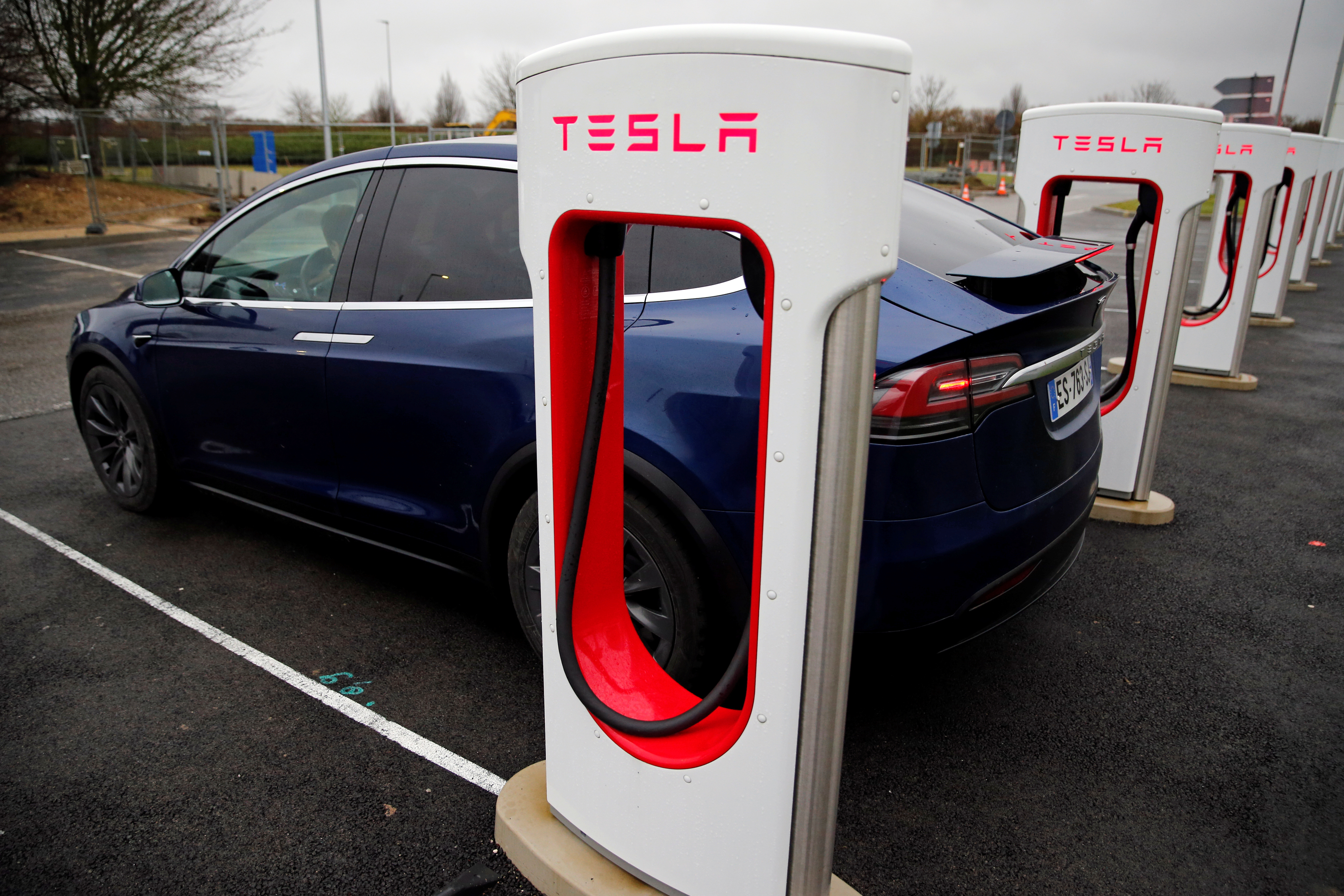A driver recharges the battery of his Tesla car at a Tesla Super Charging station in a petrol station on the highway in Sailly-Flibeaucourt