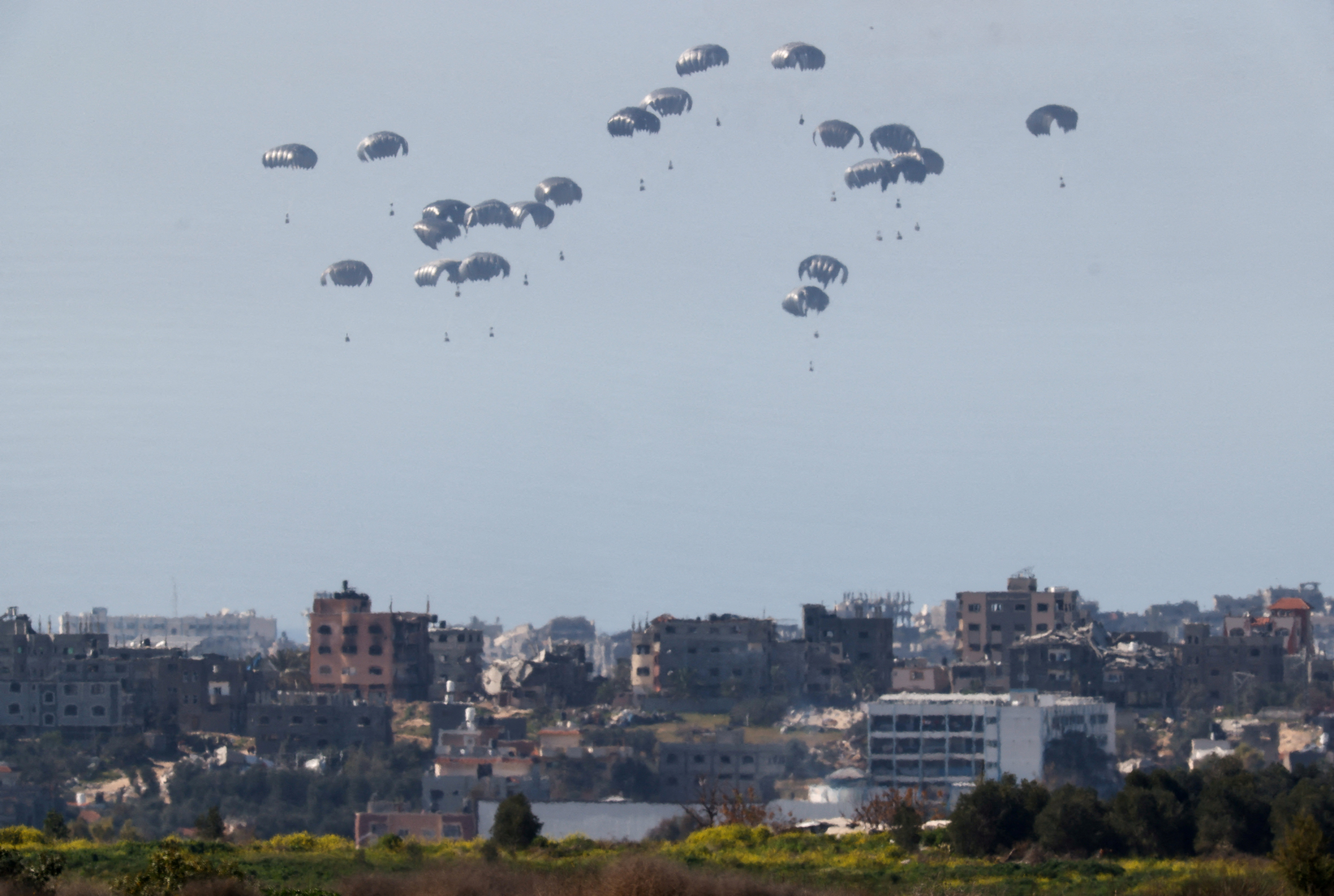 Packages dropped from a military aircraft fall towards Gaza, as seen from Israel