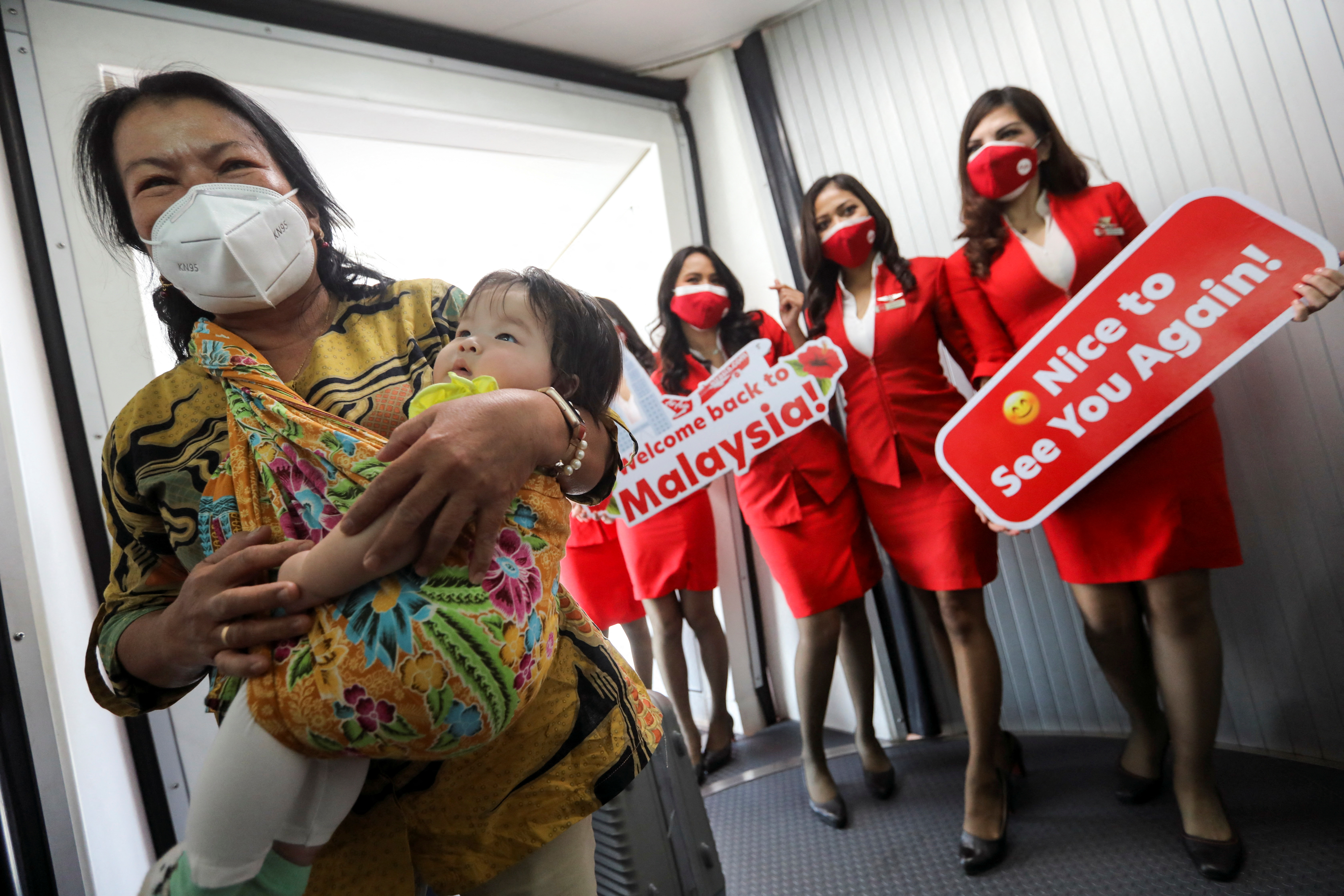 Stewardesses welcome a woman and toddler, as they disembark from an airplane from Jakarta, Indonesia at Kuala Lumpur International Airport 2 (KLIA2) in Sepang
