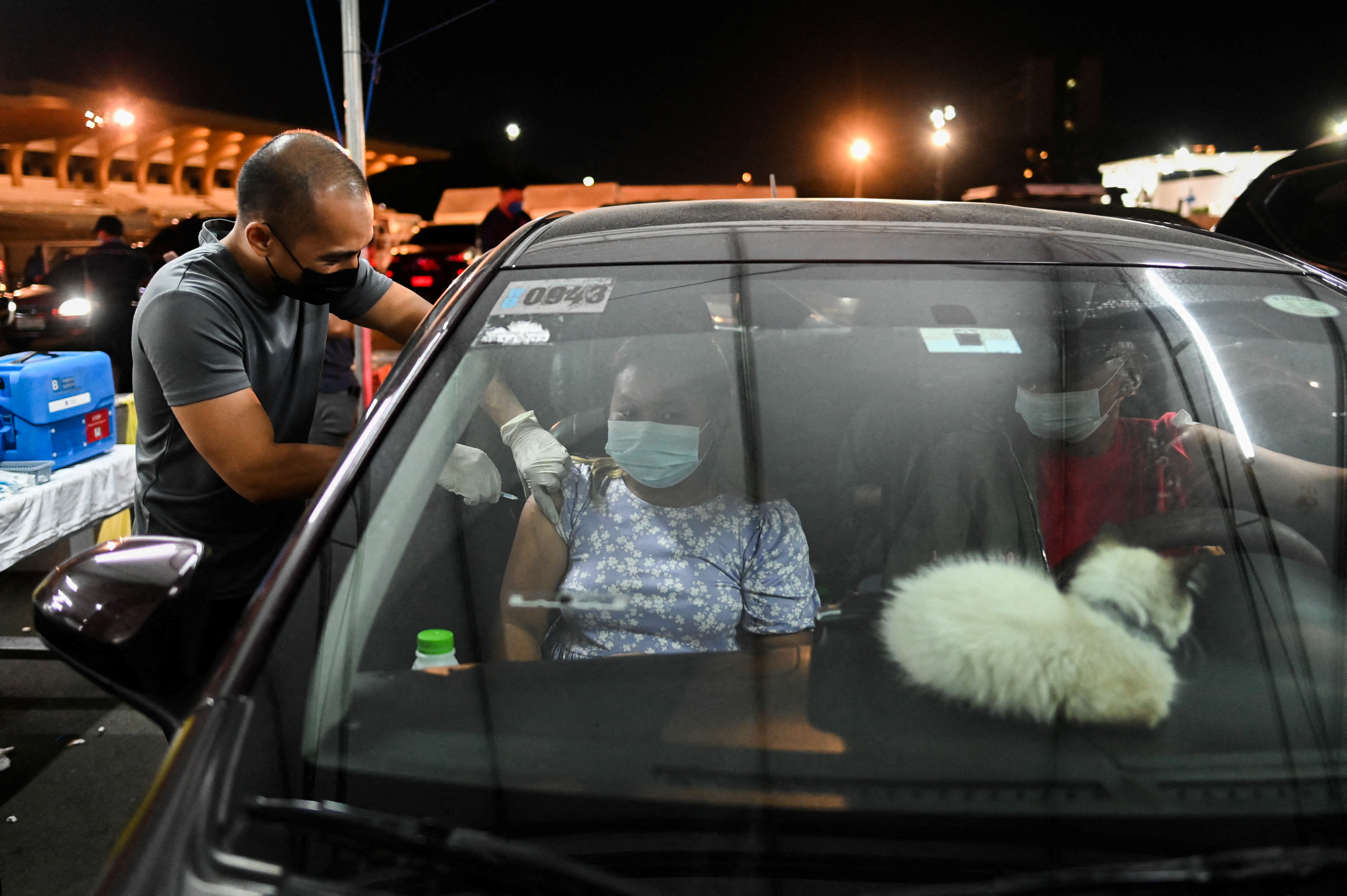 A woman receives a booster shot of the Pfizer coronavirus disease (COVID-19) vaccine, at a drive-through vaccination site, in Manila, Philippines, January 14, 2022. REUTERS/Lisa Marie David