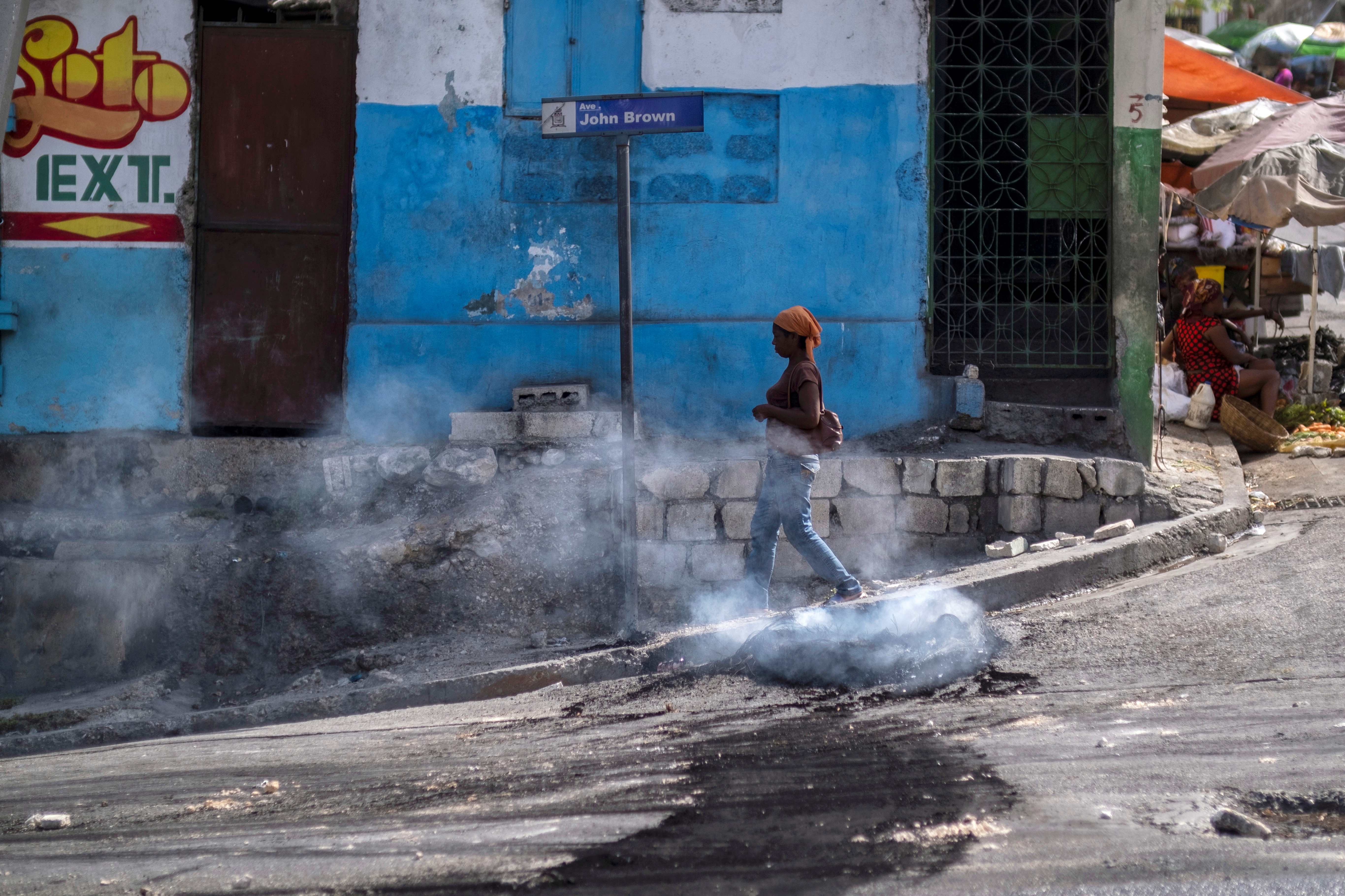 A woman walks past a smoking tire set on fire by protesters upset with growing violence in the Lalue neighborhood, a week after the assassination of President Jovenel Moise, in Port-au-Prince, Haiti July 14, 2021. REUTERS/Ricardo Arduengo