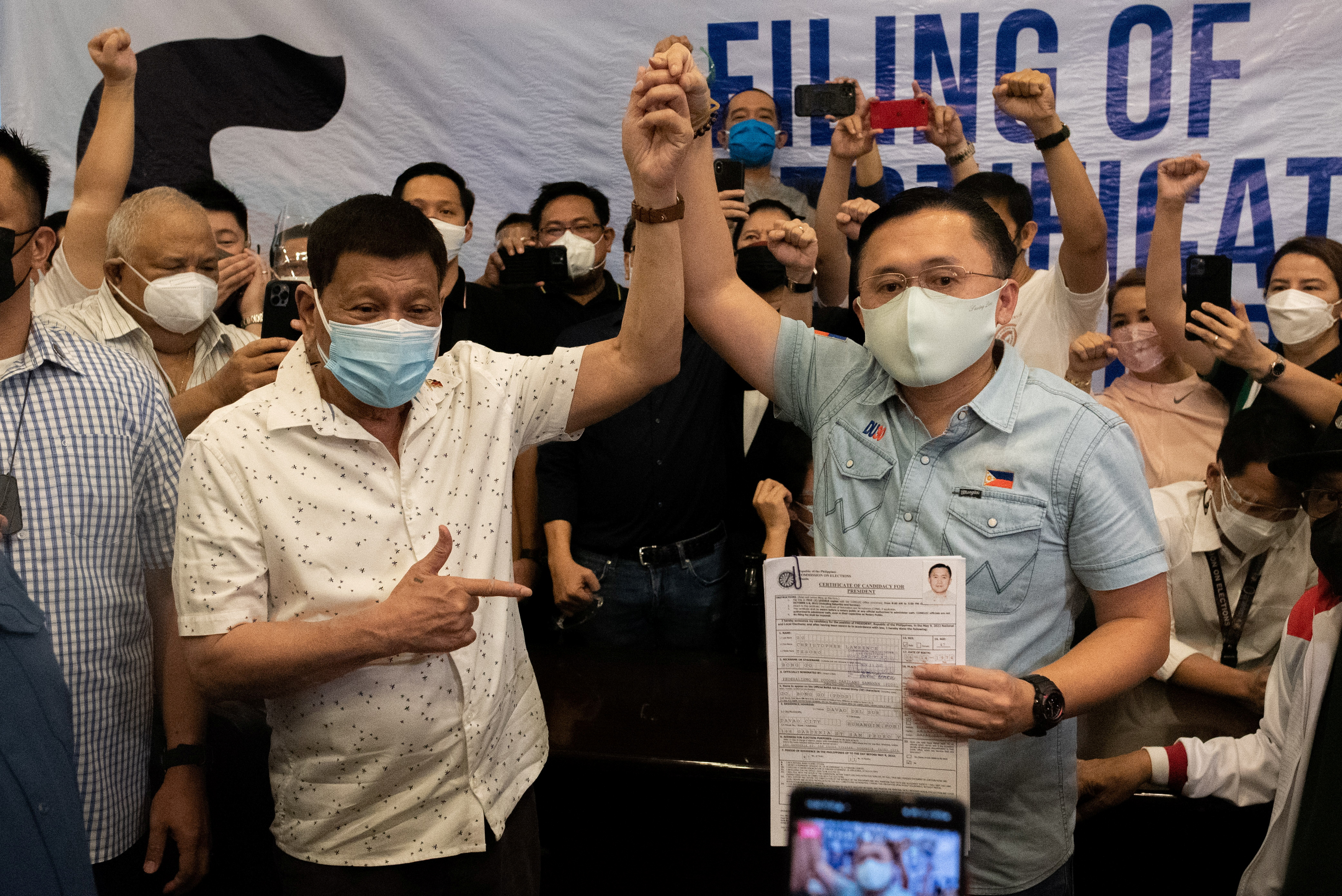 Philippine President Rodrigo Duterte raises the hand of Philippine Senator Christopher 