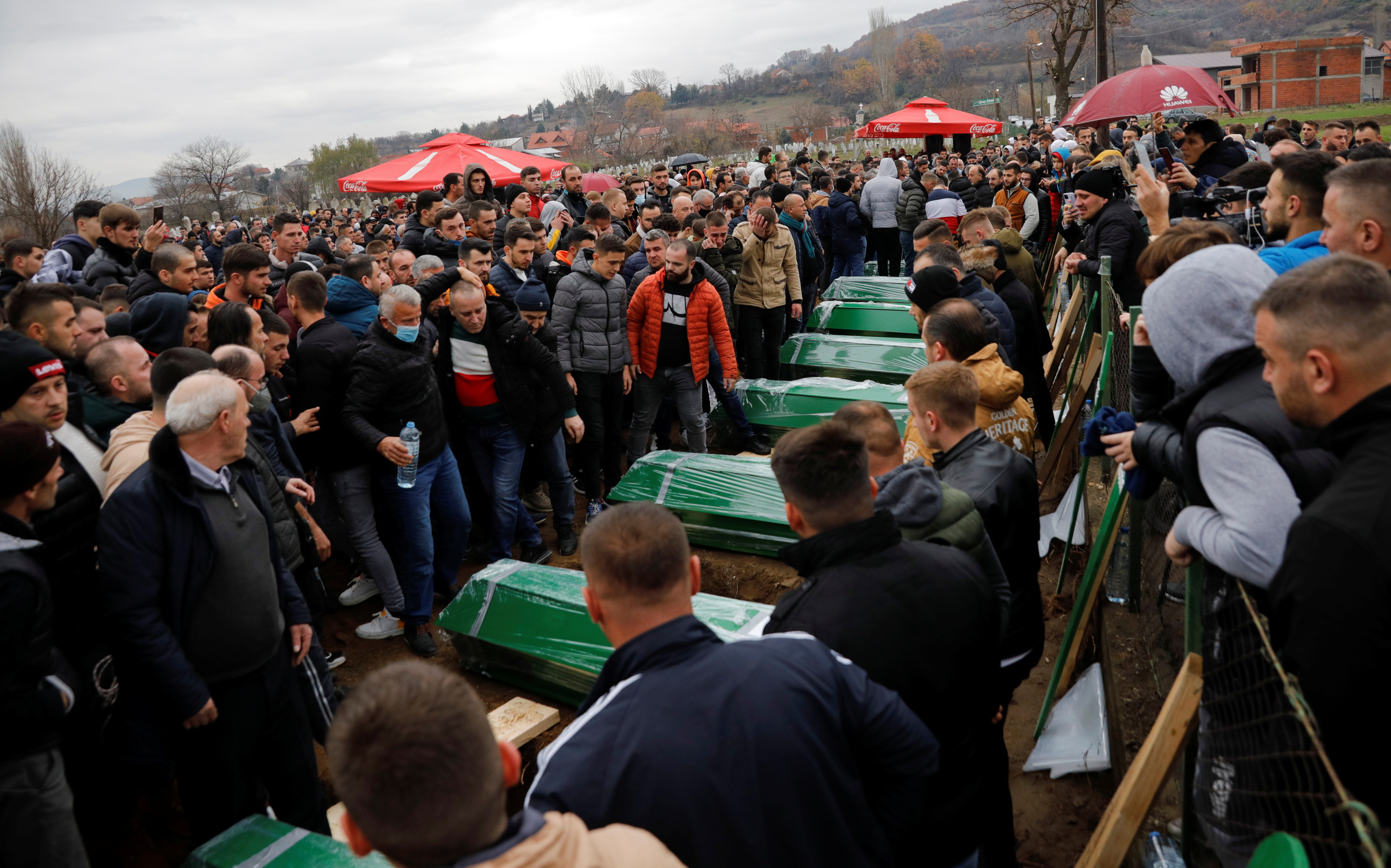 People mourn by the coffins during the burial ceremony for the victims of last week's deadly bus crash in Bulgaria, in the village of Morane, near Skopje, North Macedonia December 3, 2021. REUTERS/Ognen Teofilovski
