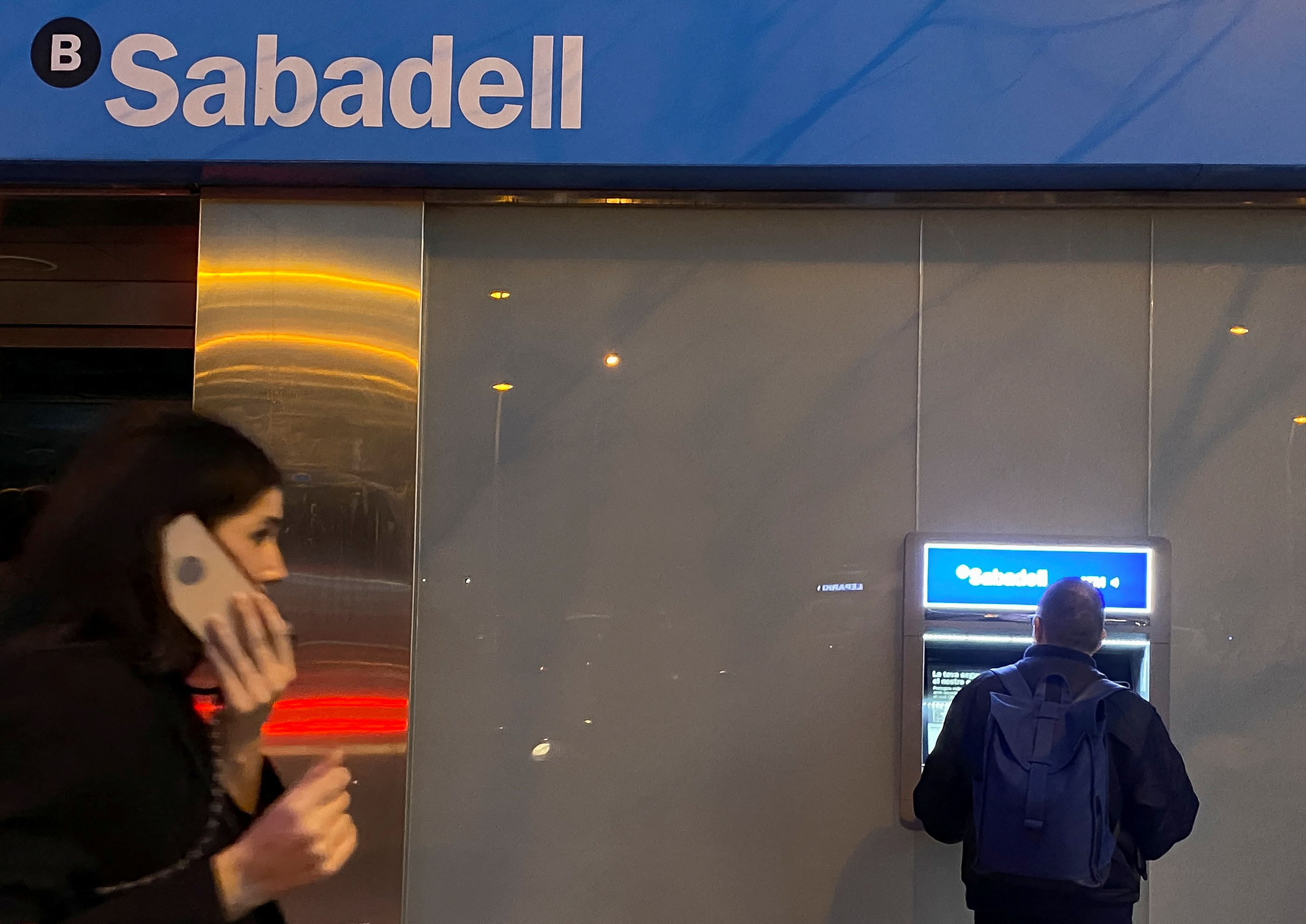 A man uses an ATM at Sabadell bank office in Barcelona