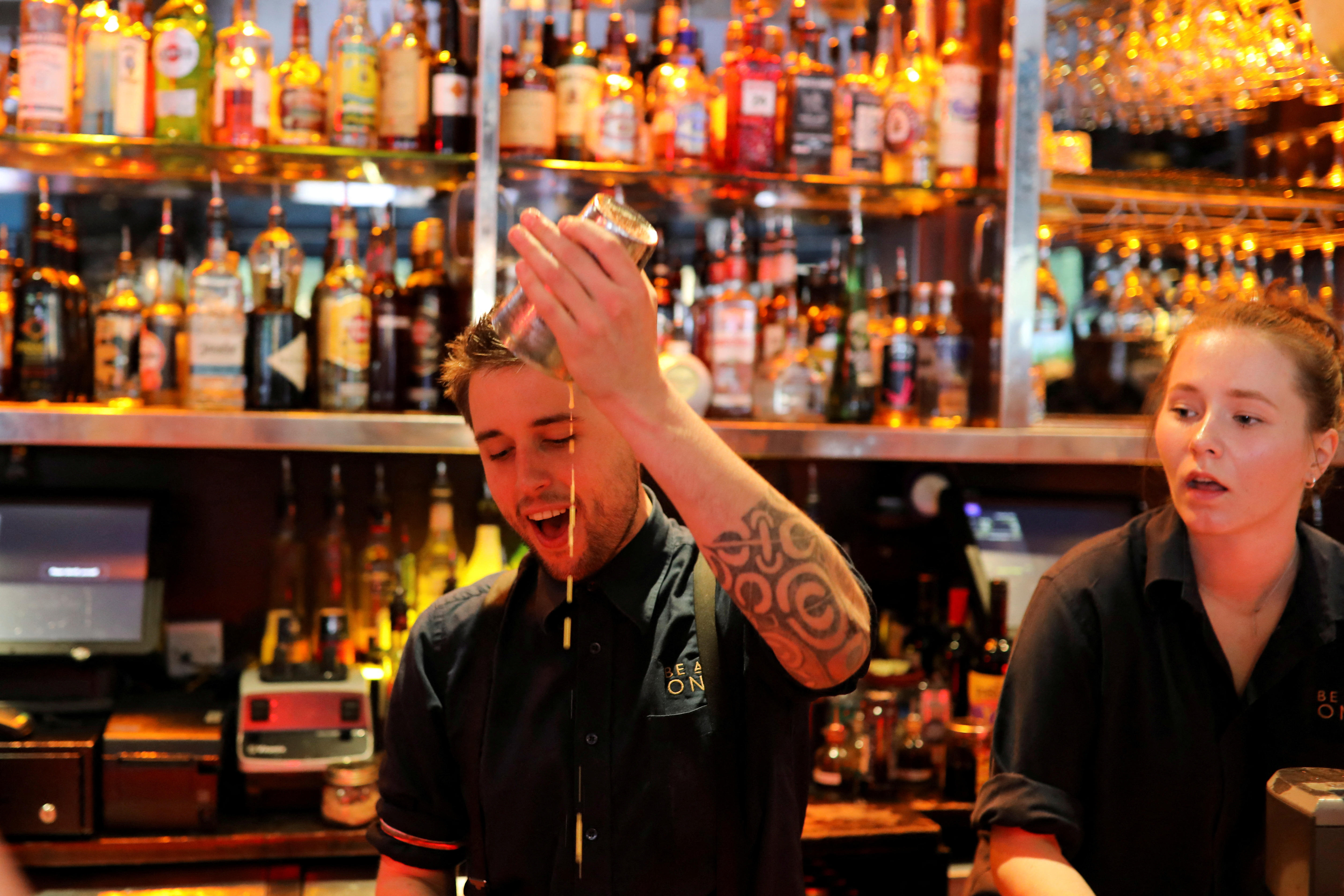 A bartender makes cocktails in a bar in central London