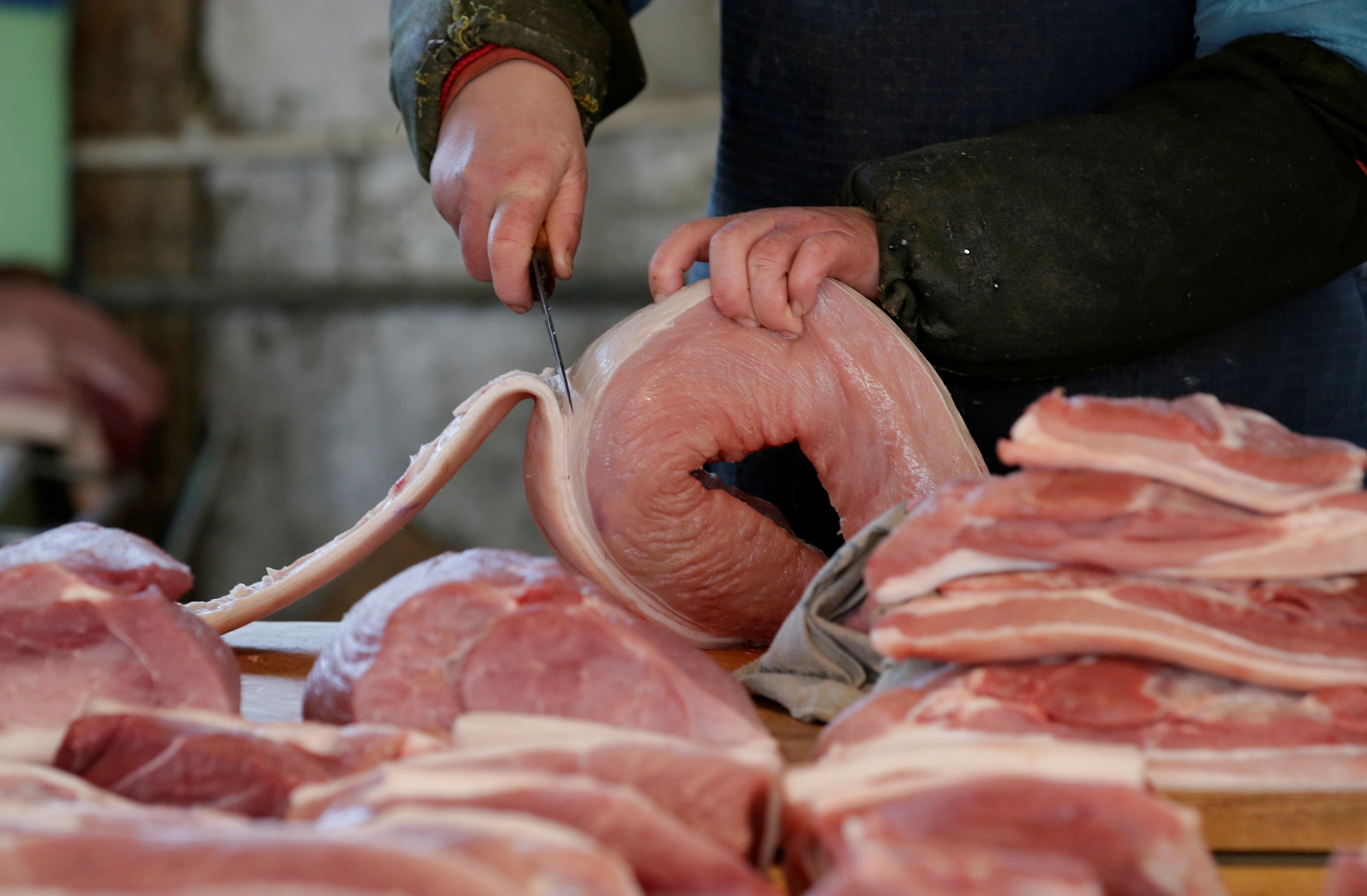 A butcher cuts a piece of pork at a market in Beijing