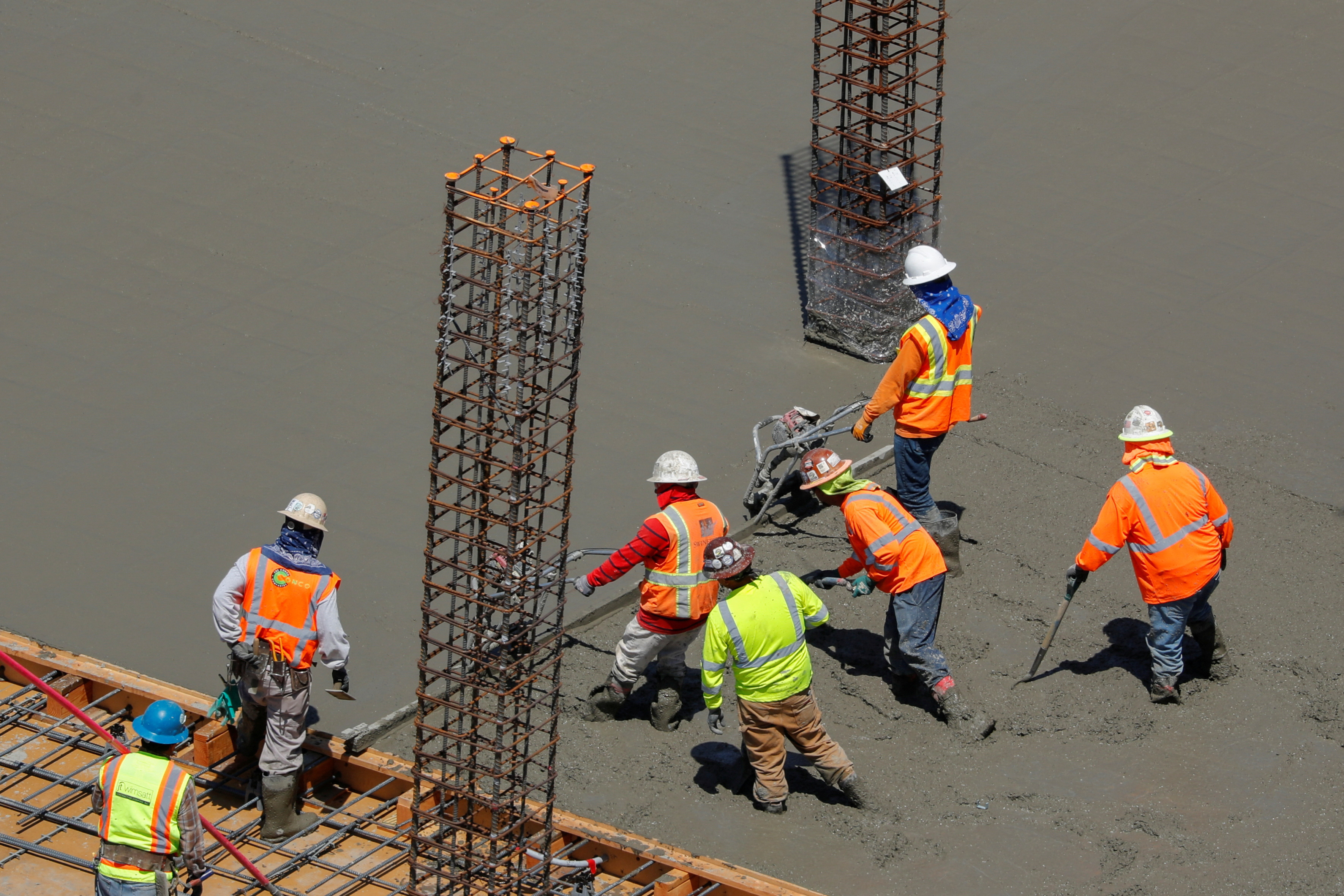 Workers pour cement at a construction site for an office town in downtown San Diego