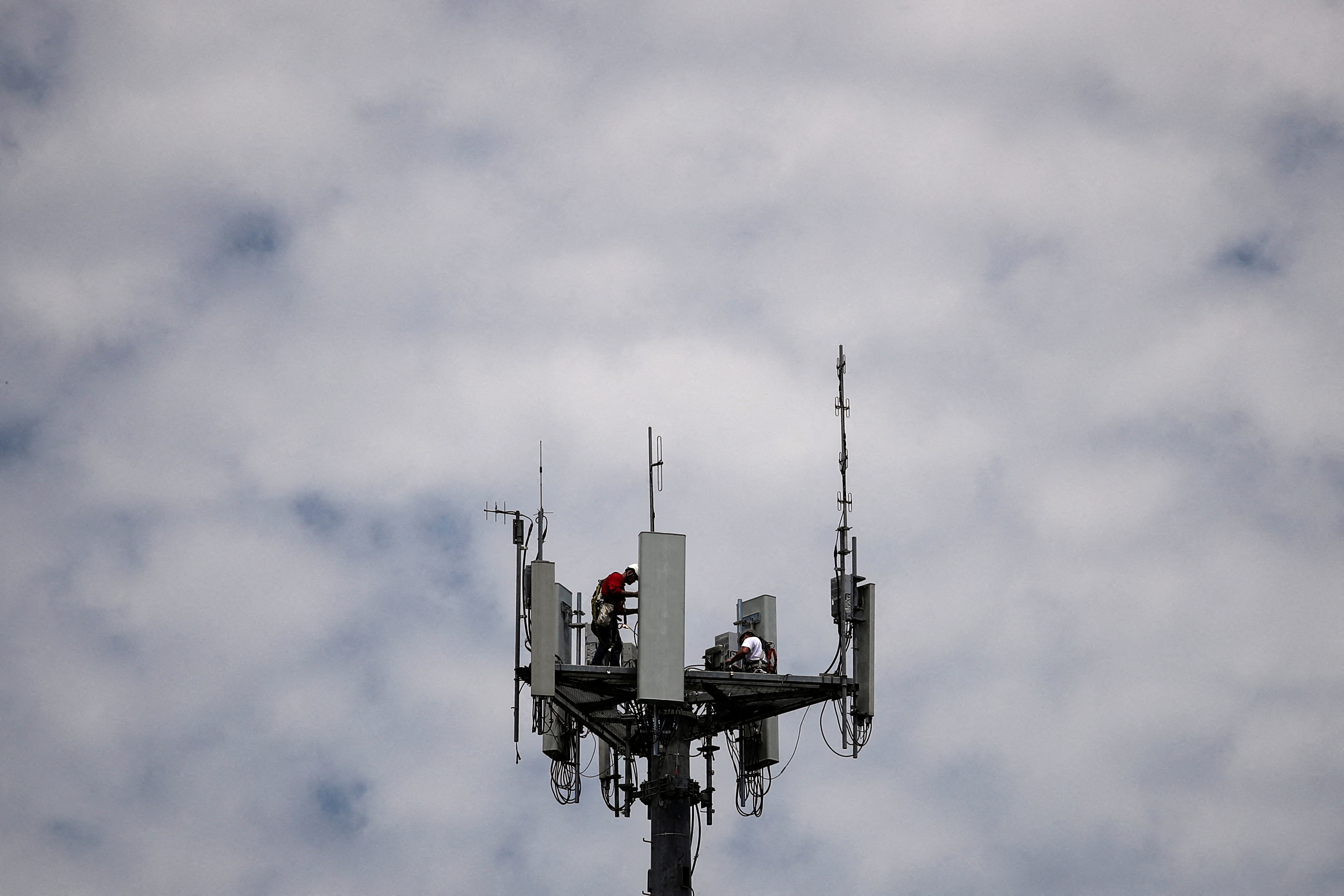 Workers install 5G telecommunications equipment on a T-Mobile tower in Seabrook, Texas