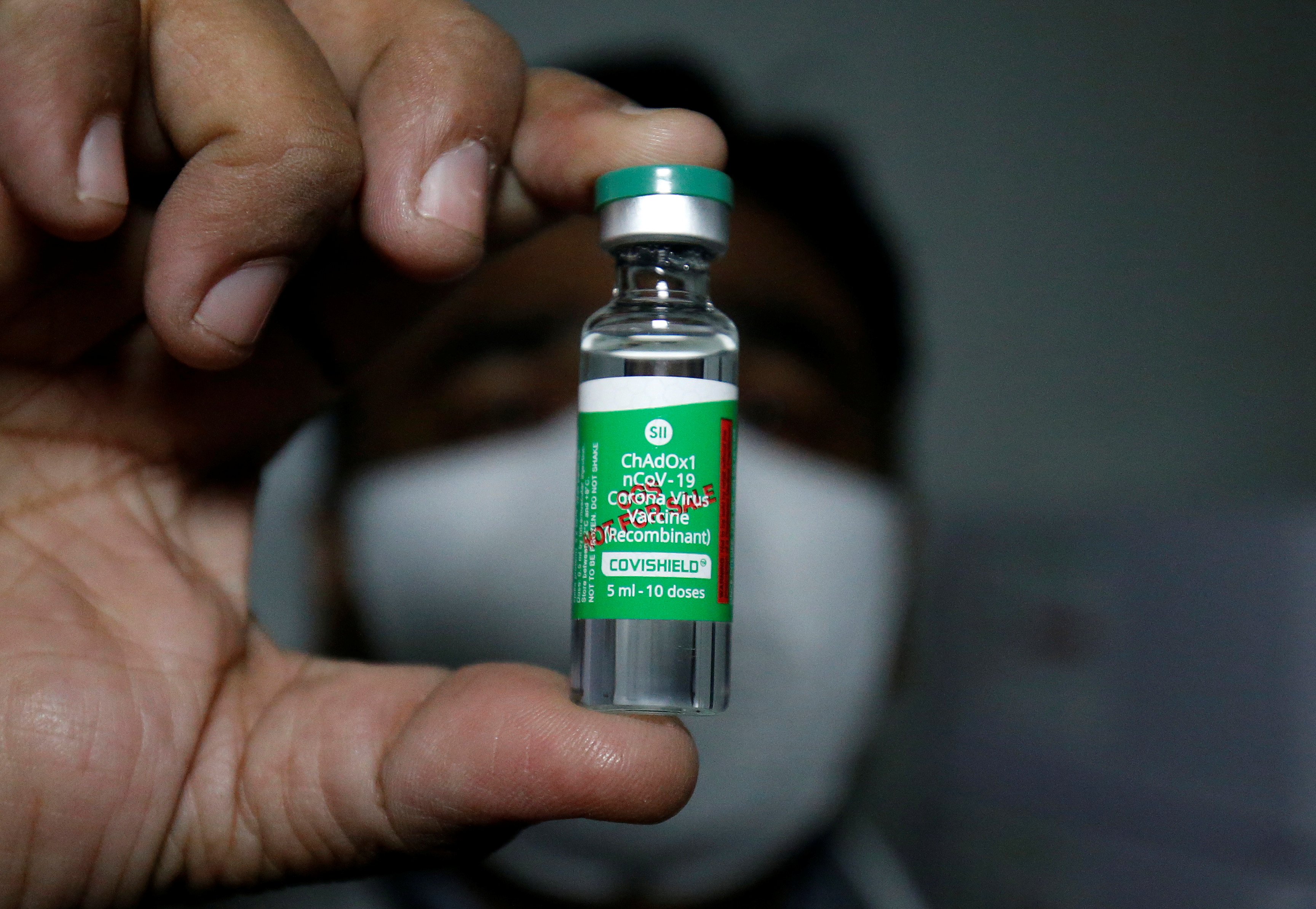 An official displays a vial containing COVISHIELD after a consignment of the vaccines arrived from the western city of Pune for its distribution, in Ahmedabad