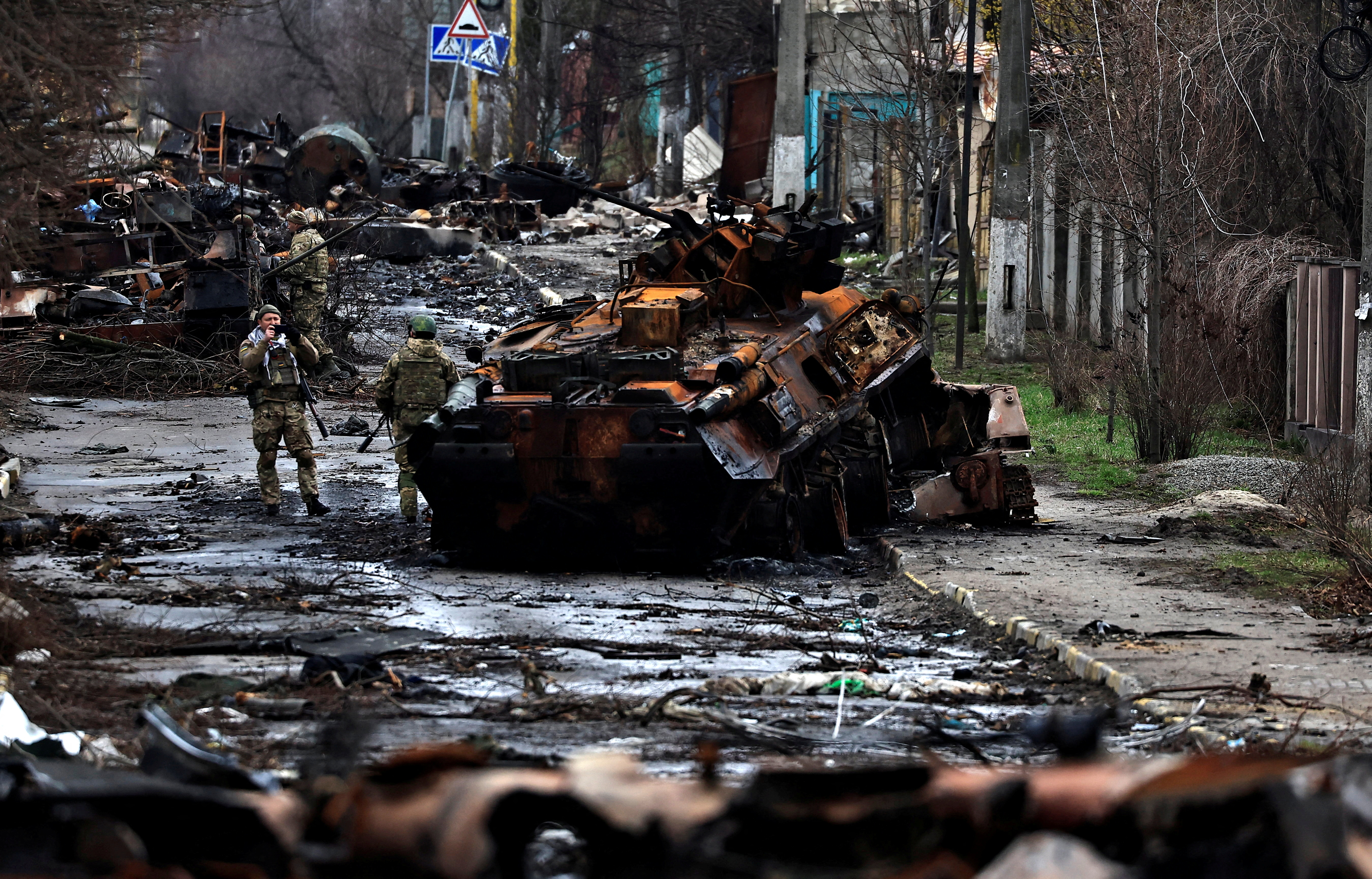 Un soldato scatta una fotografia del suo compagno mentre posa accanto a un carro armato russo distrutto e veicoli blindati, durante l'invasione russa dell'Ucraina a Bucha, nella regione di Kiev
