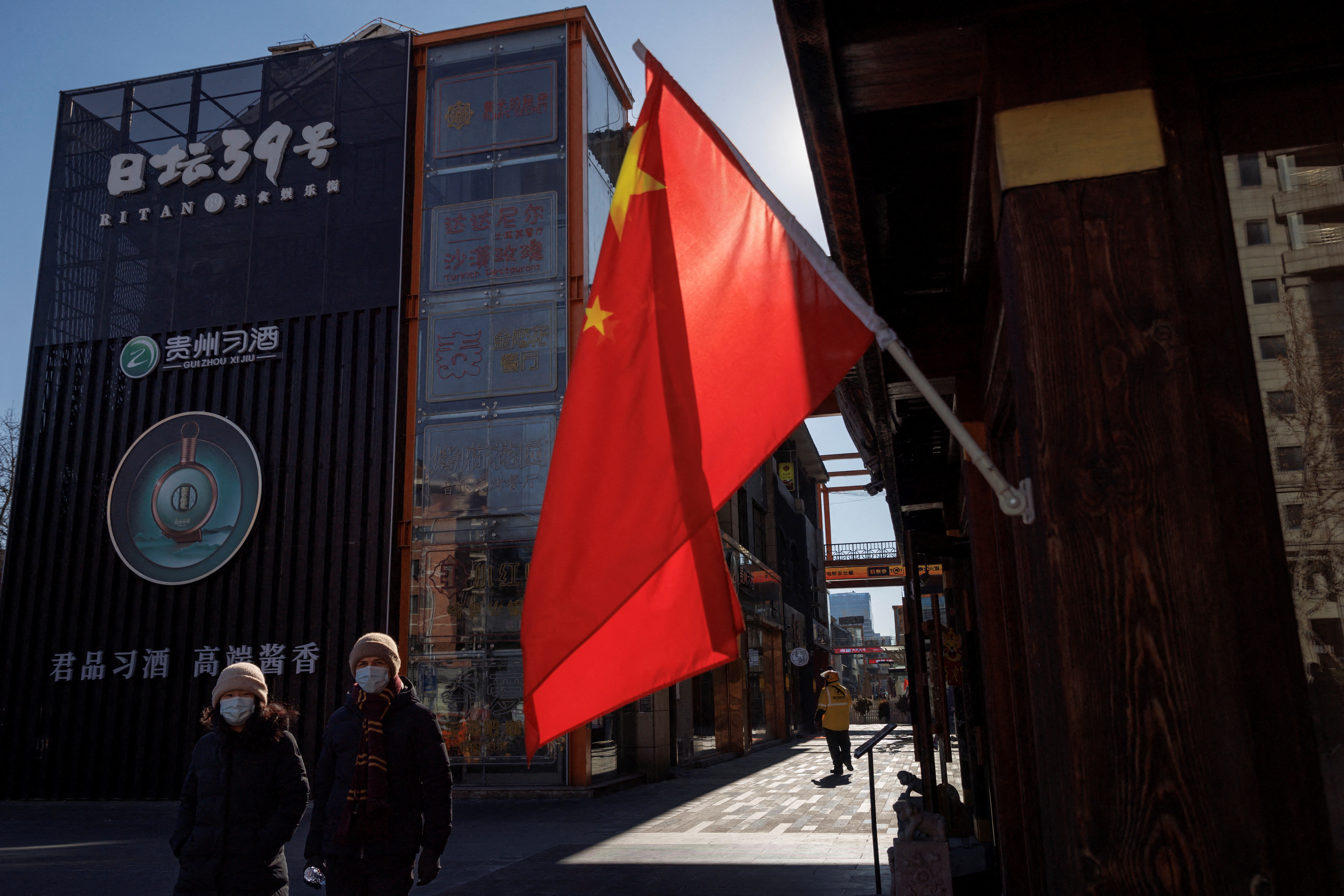 People walk past the Chinese national flag as the coronavirus disease (COVID-19) outbreak continues in Beijing
