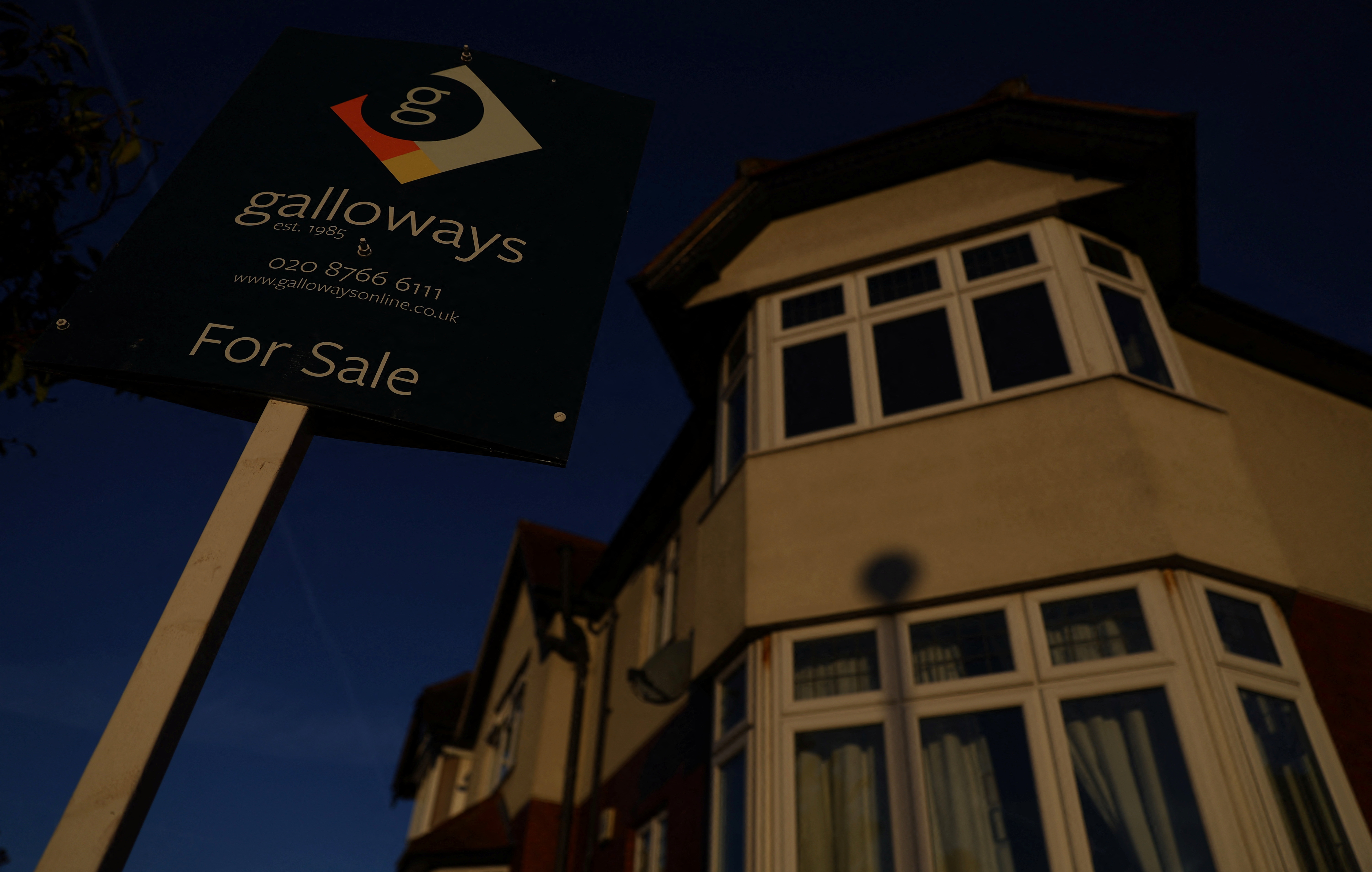 A ‘For Sale” sign is seen outside a residential house during sunrise in London