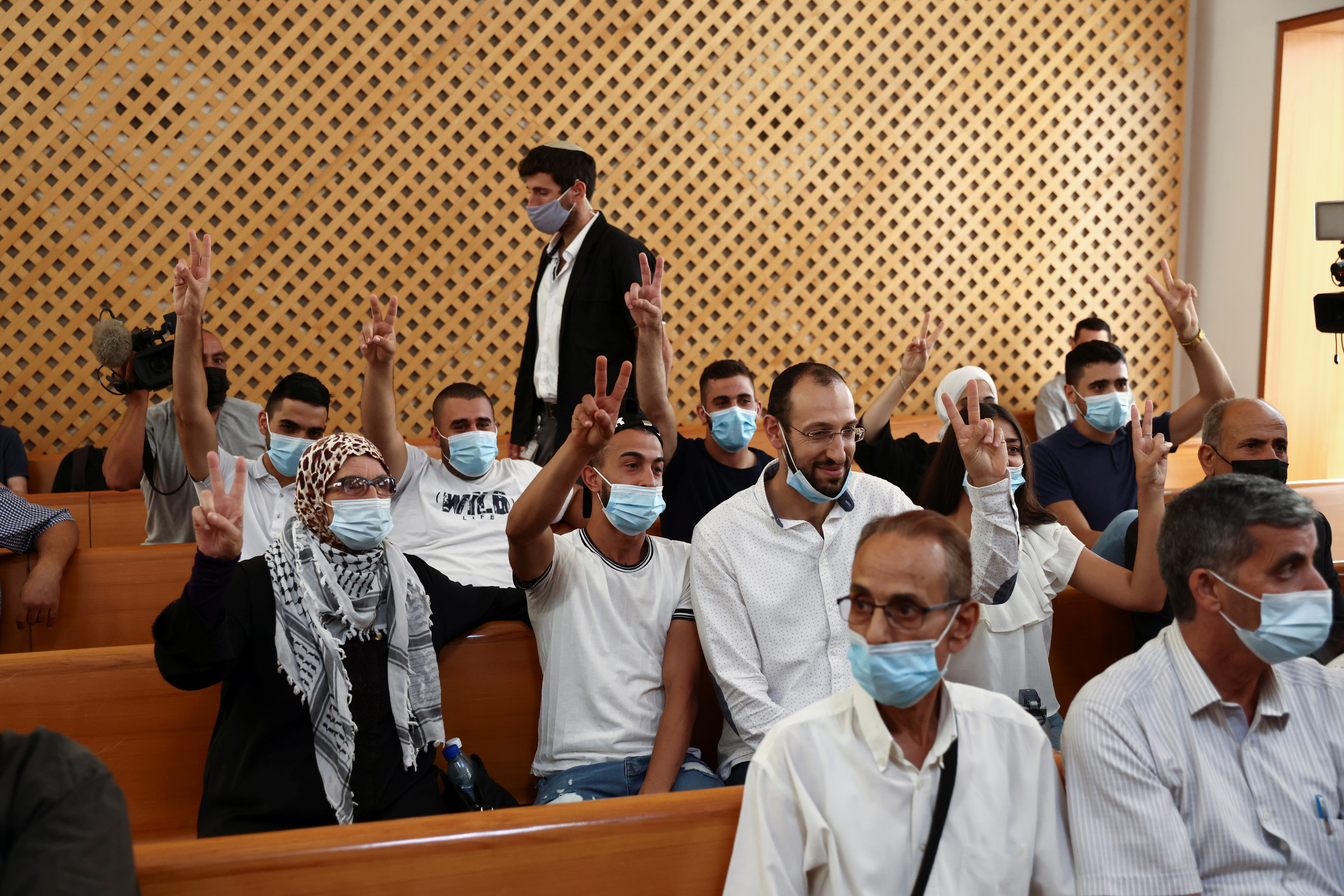 Members of the El-Kurd family, Palestinian residents of Sheikh Jarrah neighbourhood in East Jerusalem who are facing eviction, and a supporter of the family, flash victory signs during a court hearing, in the Israeli Supreme Court, in Jerusalem