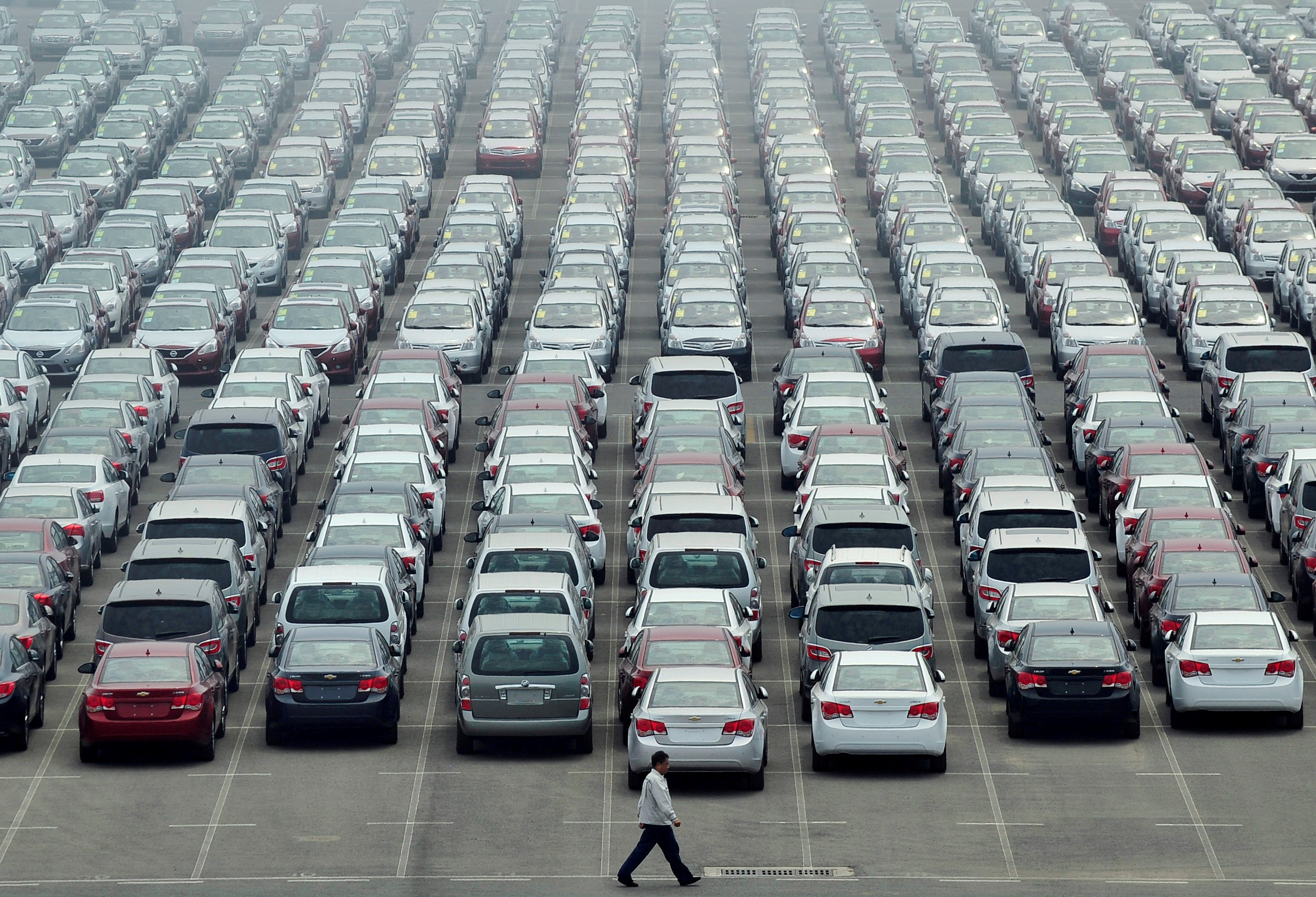 A man walks past a parking lot at Dayaowan port of Dalian