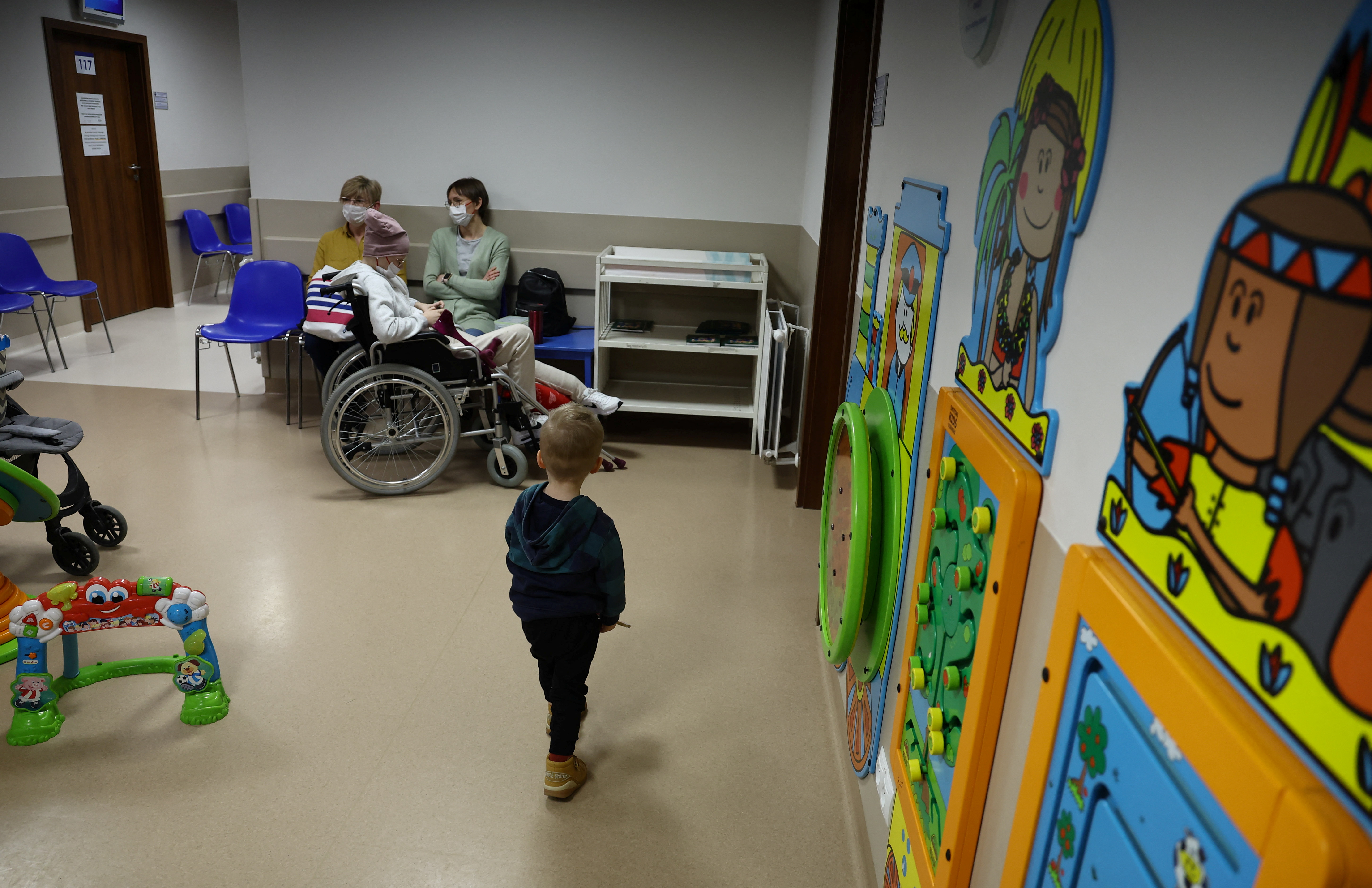 People wait outside the examination room of children's oncology ward at the Institute of Mother and Child hospital, in Warsaw