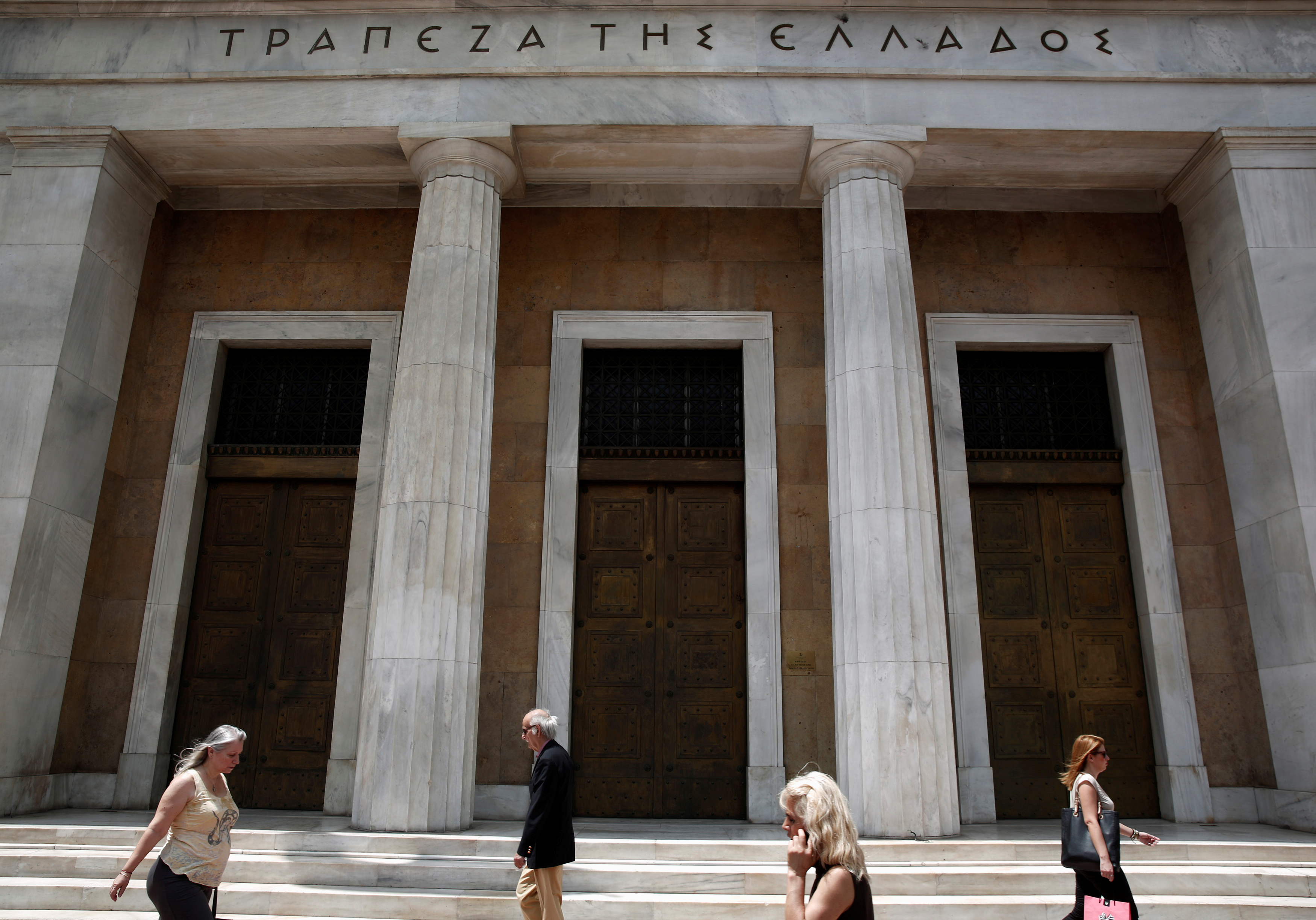 People make their way in front of the Bank of Greece in Athens