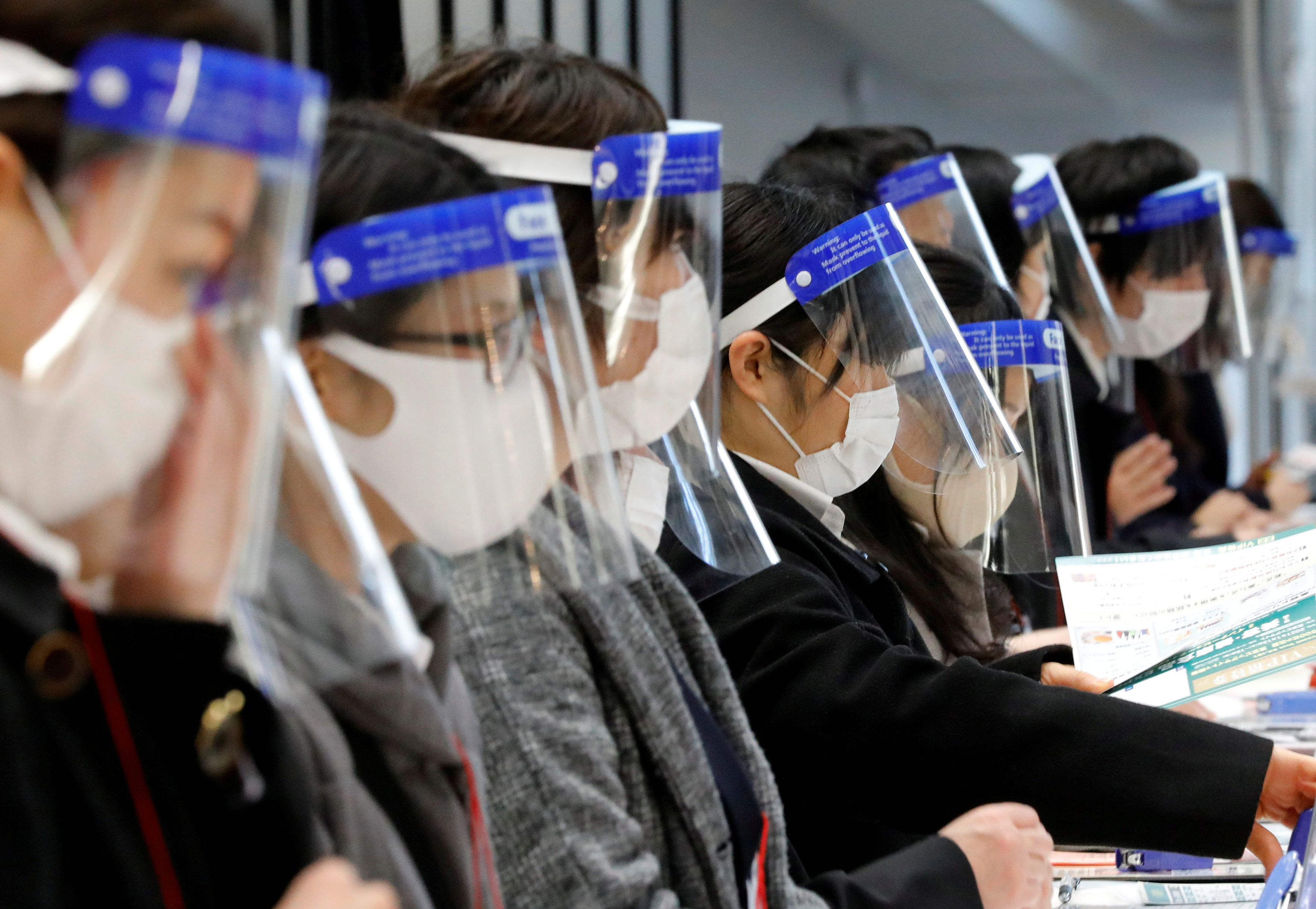 Staff wearing protective face shields amid the coronavirus disease (COVID-19) outbreak work at a reception desk at an exhibition centre in Tokyo, Japan, January 13, 2021. REUTERS/Kim Kyung-Hoon/File Photo
