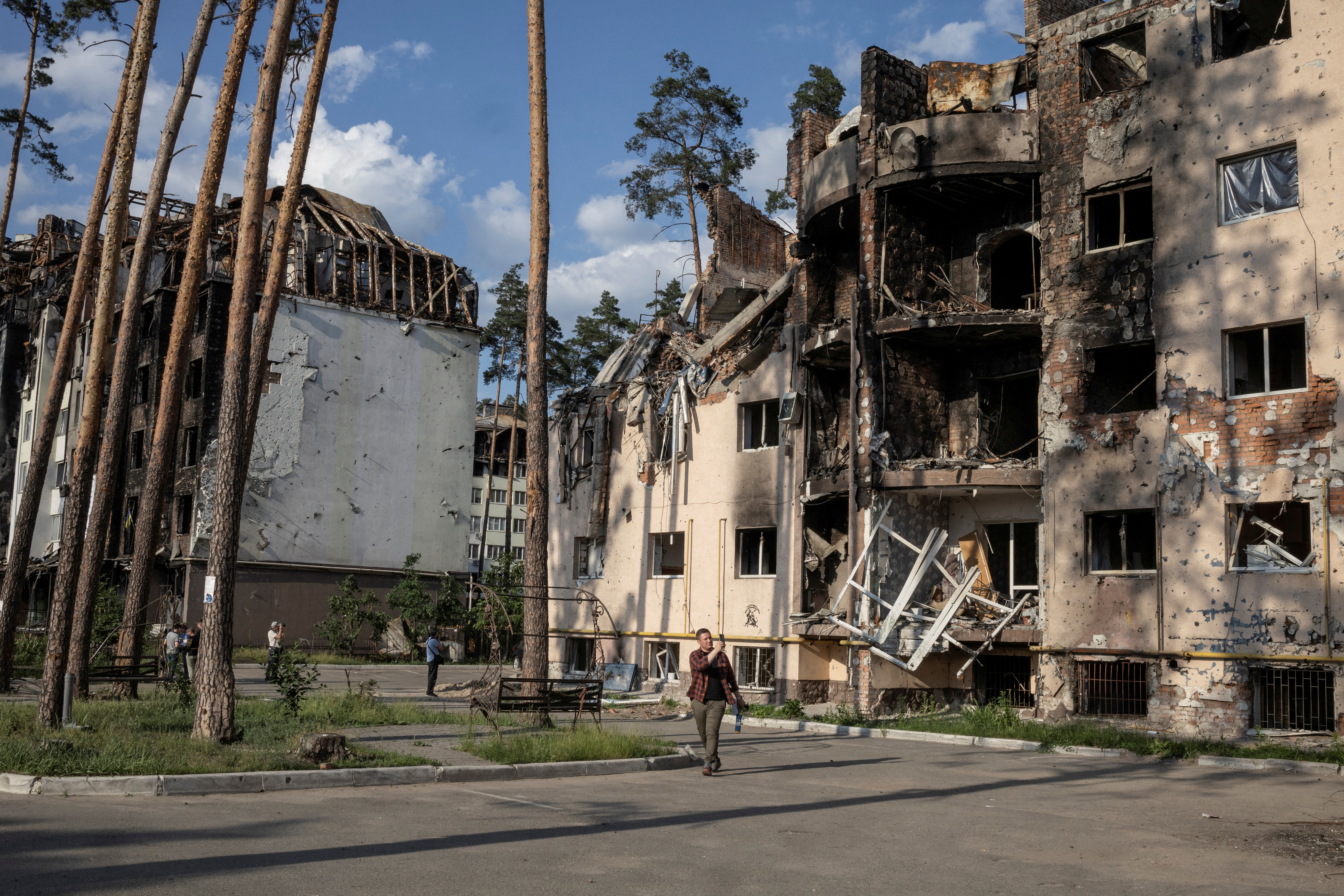 People look at destroyed buildings in Irpin, outside Kyiv, as Russia's attacks on Ukraine continues