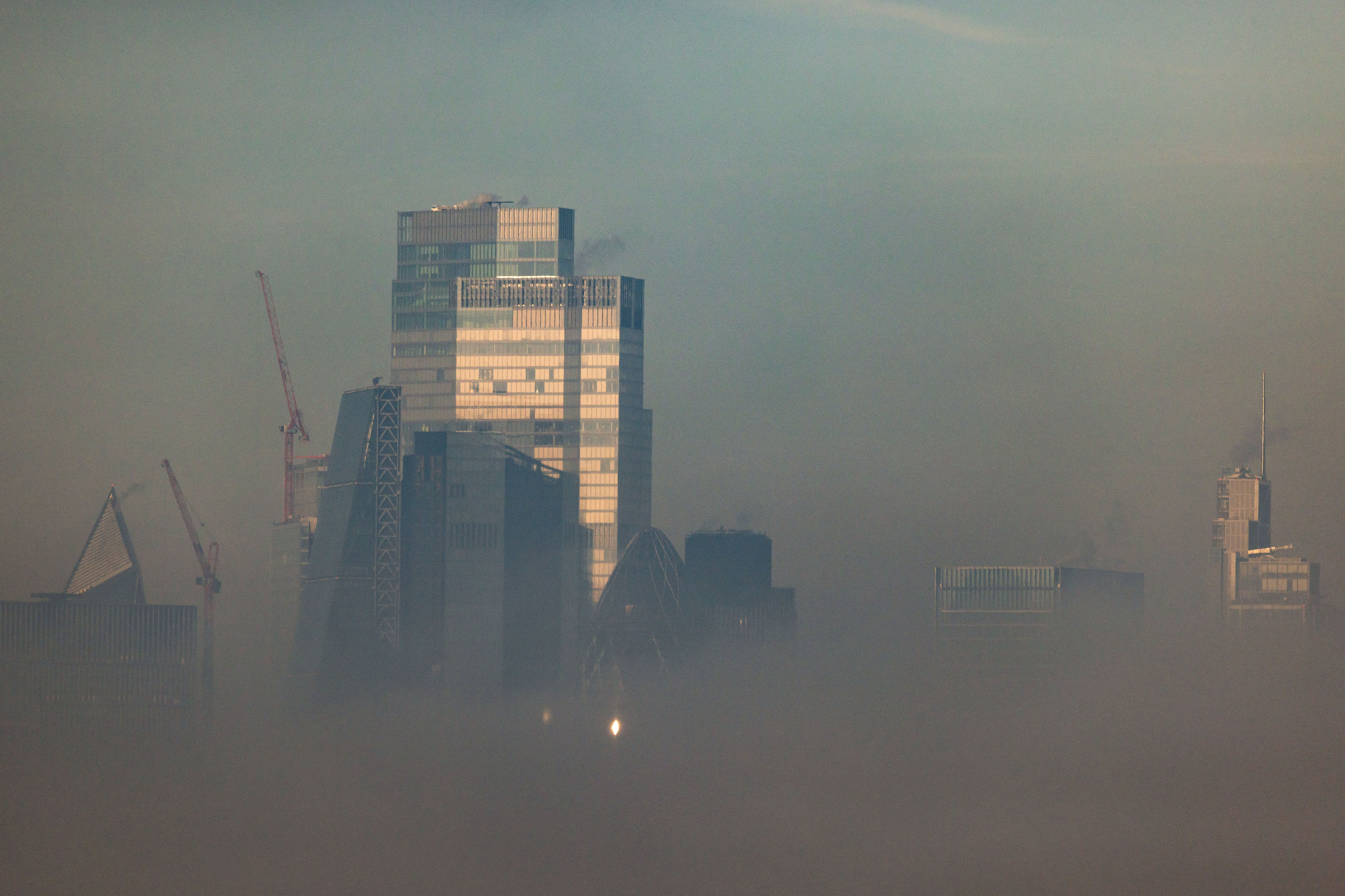 Buildings in the city financial district are seen through fog from Canary Wharf