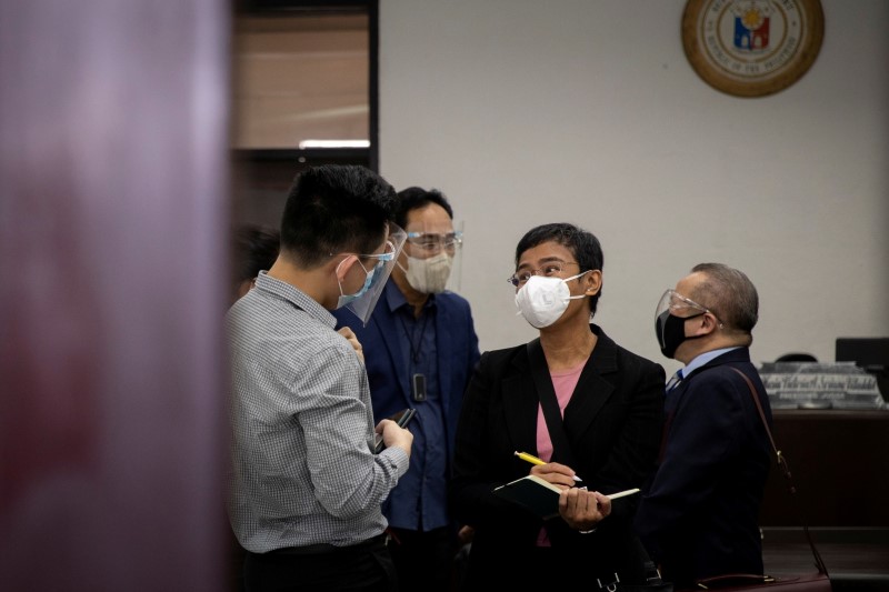 Filipino journalist and Rappler CEO Maria Ressa talks to co-accused Rappler reporter Rambo Talabong inside a courtroom in Manila, Philippines