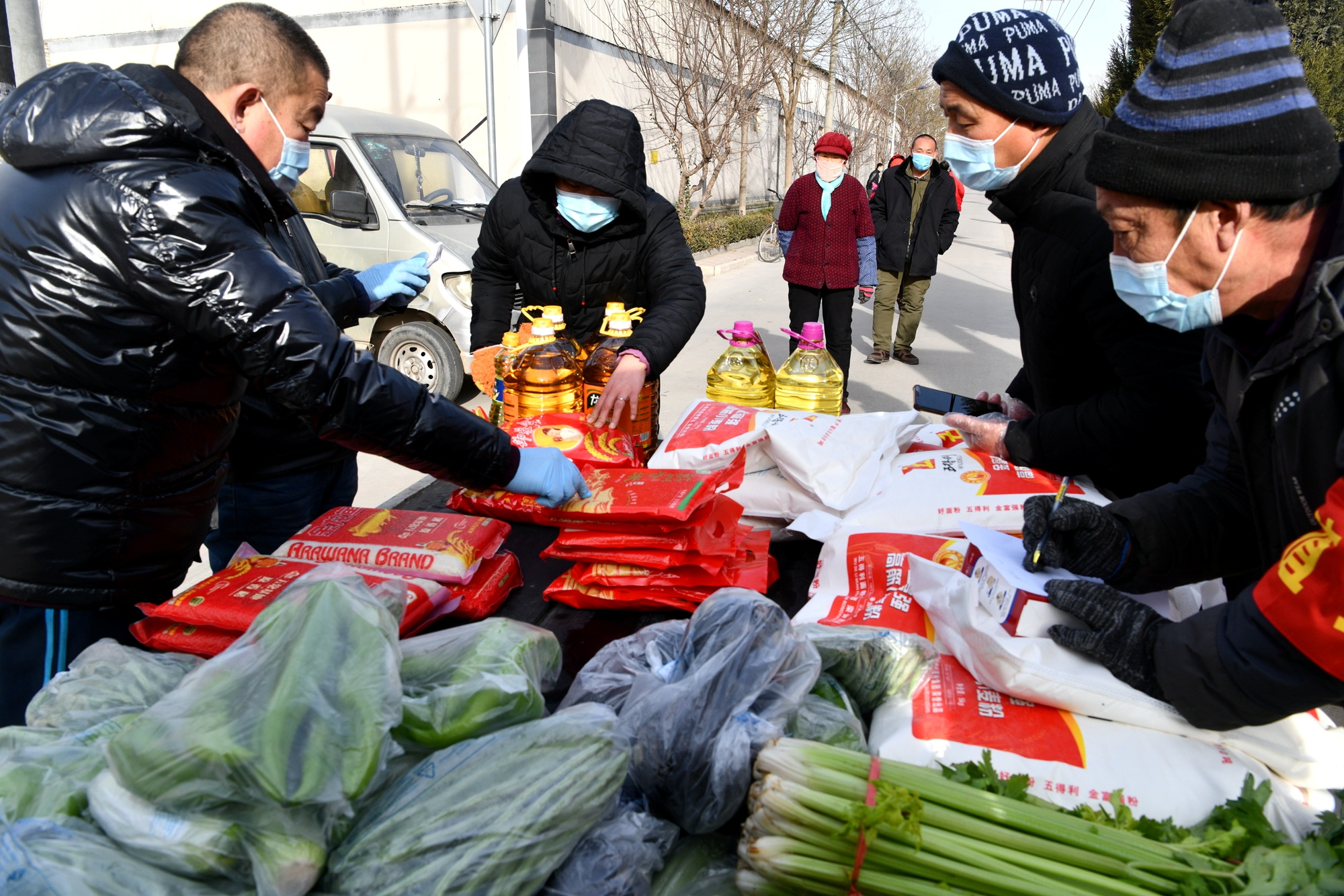 Volunteers distribute groceries to villagers at an entrance to Longhua village in Shijiazhuang
