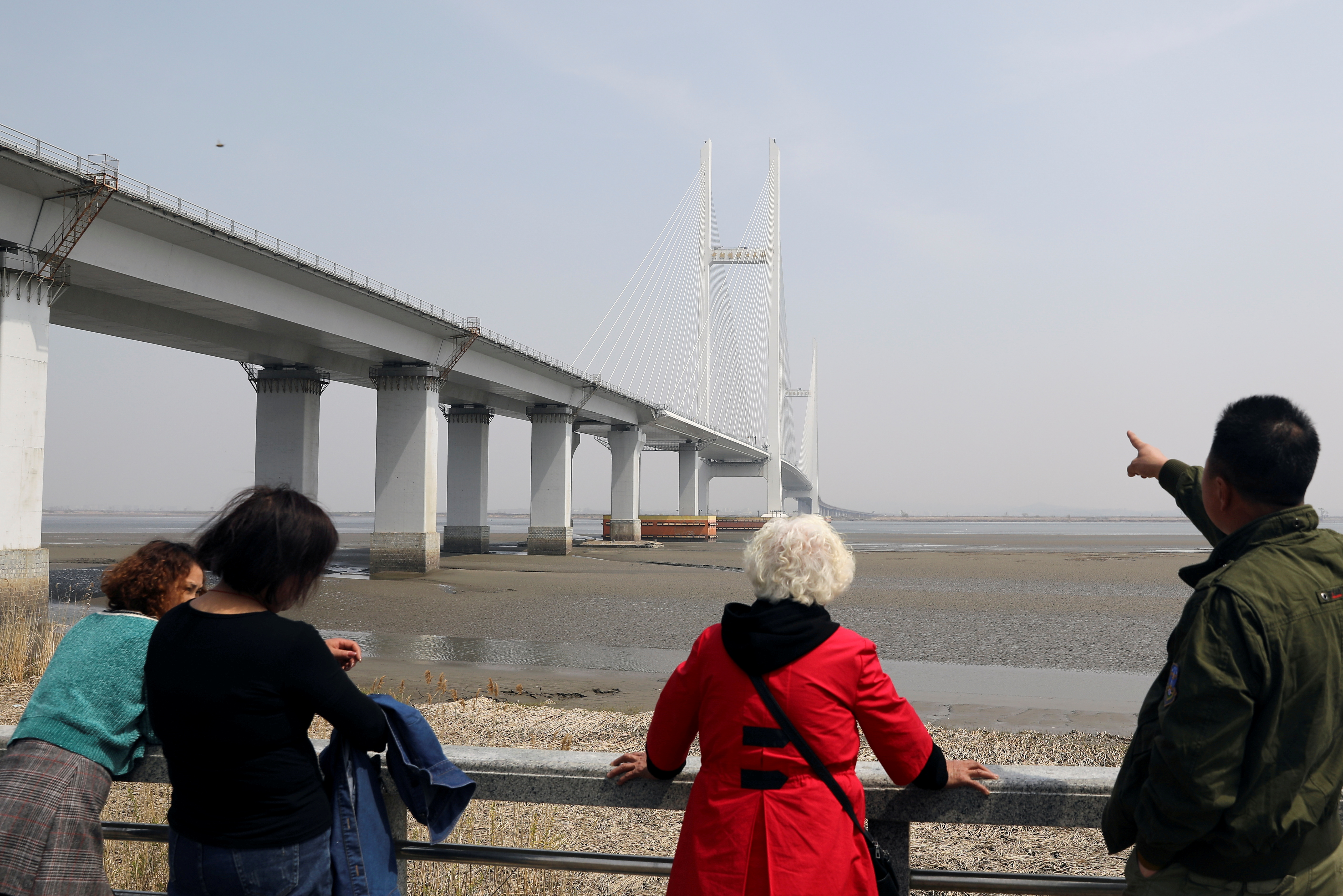 A man points at the New Yalu River Bridge designed to connect China's Dandong New Zone and North Korea's Sinuiju, in Dandong, Liaoning province, China April 20, 2021. Picture taken April 20, 2021.  REUTERS/Tingshu Wang/File Photo